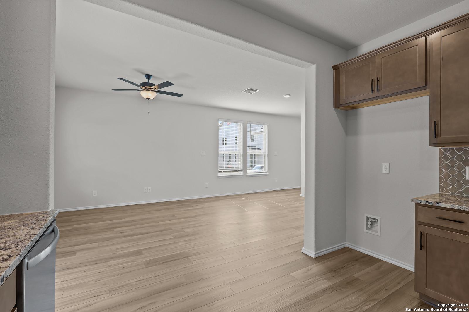 Open-concept kitchen with shaker cabinets, granite counters, and subway tile backsplash opening to living room in Davidson Homes The Florence C, San Antonio