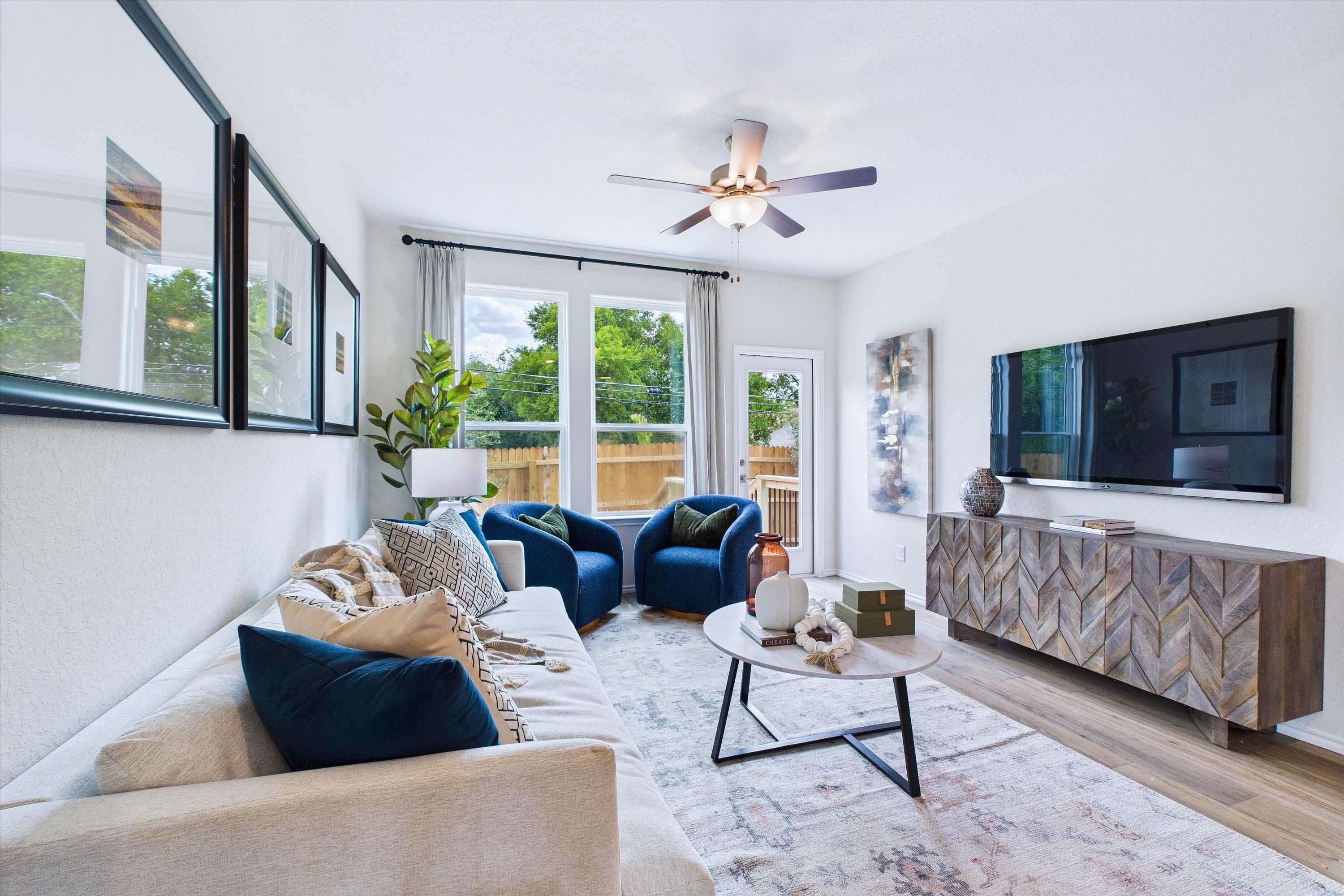 Modern living room in The Gillian C home design featuring a neutral sofa, blue accent chairs, and a chevron media console.