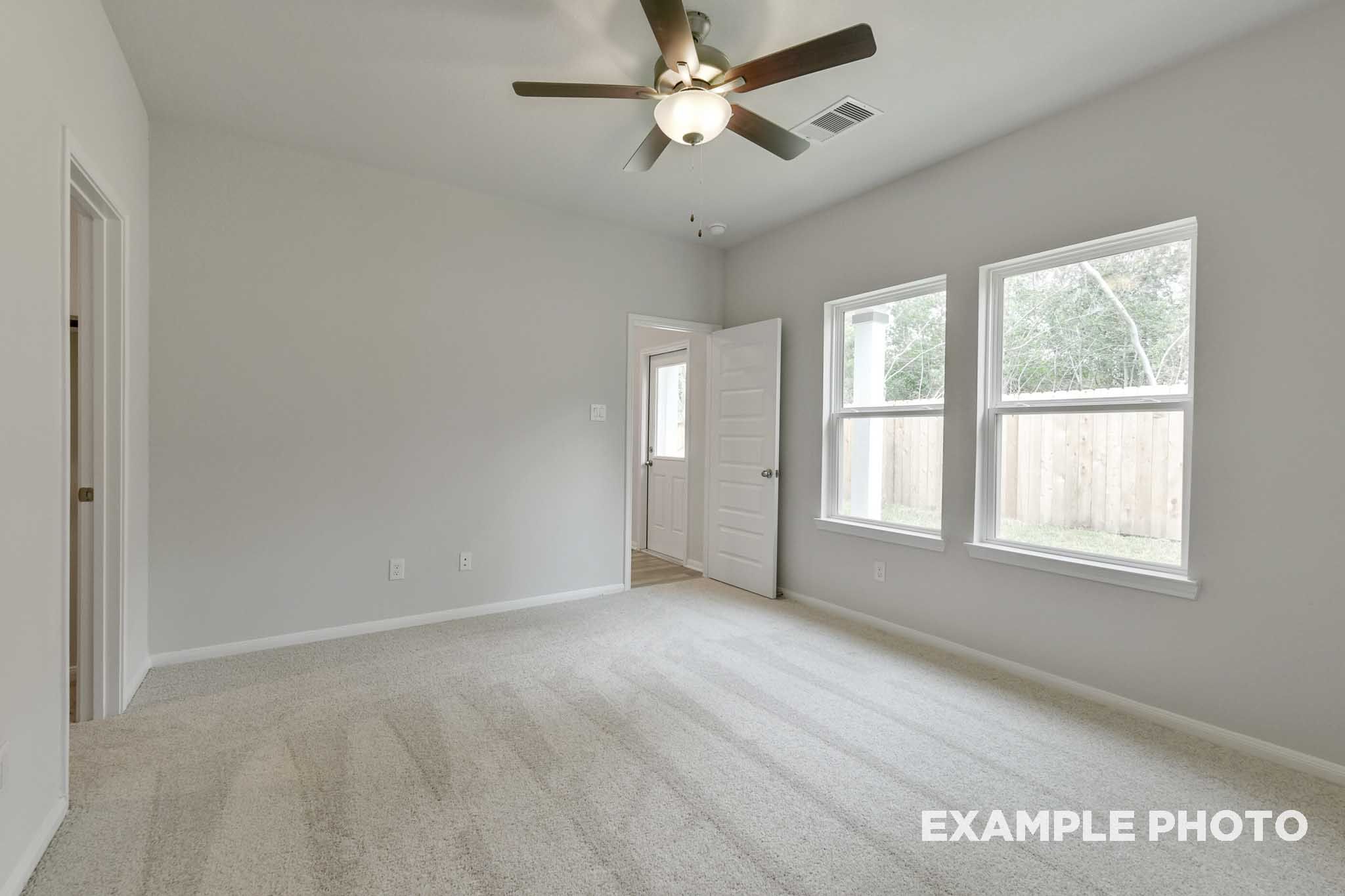 Spacious master suite with carpeted flooring and ceiling fan in The Frio home design by Davidson Homes in Conroe, Texas.