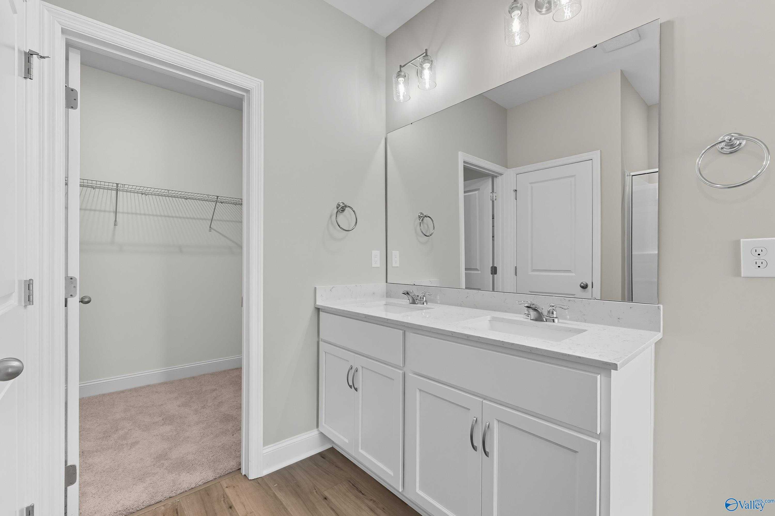 Modern master bath with double vanity, large mirror, and open walk-in closet in Davidson Homes The Franklin, Meridianville, Alabama