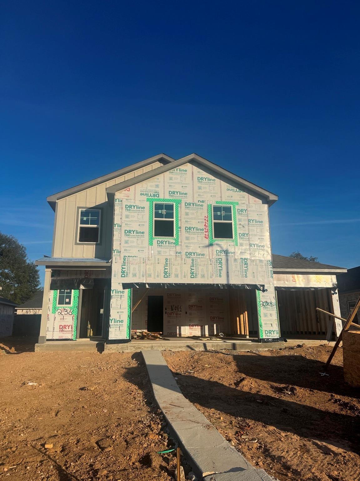 Two-story 5-bedroom home under construction with sheathed exterior, windows, and 3-car garage in Windmill Estates, Magnolia, Texas