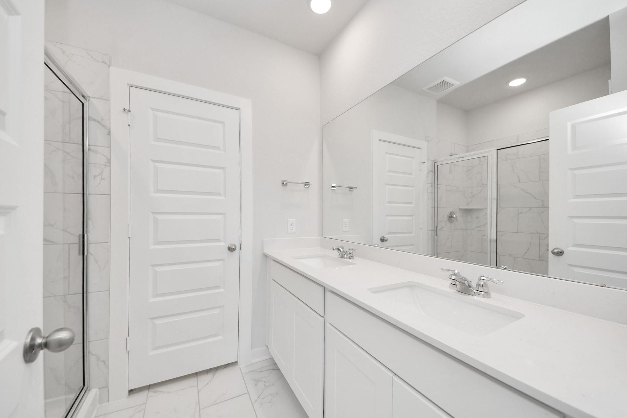 Modern bathroom with double vanity and tiled walk-in shower in The Sabine F floor plan at Liberty Estates, Cleveland, TX.