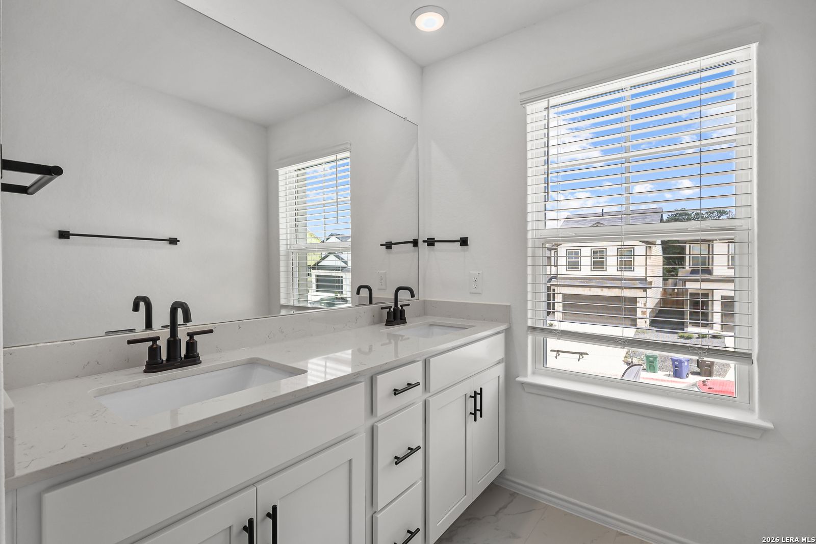 Modern bathroom with double vanity, quartz countertops, and matte black fixtures in The Gillian C home, San Antonio, Texas.