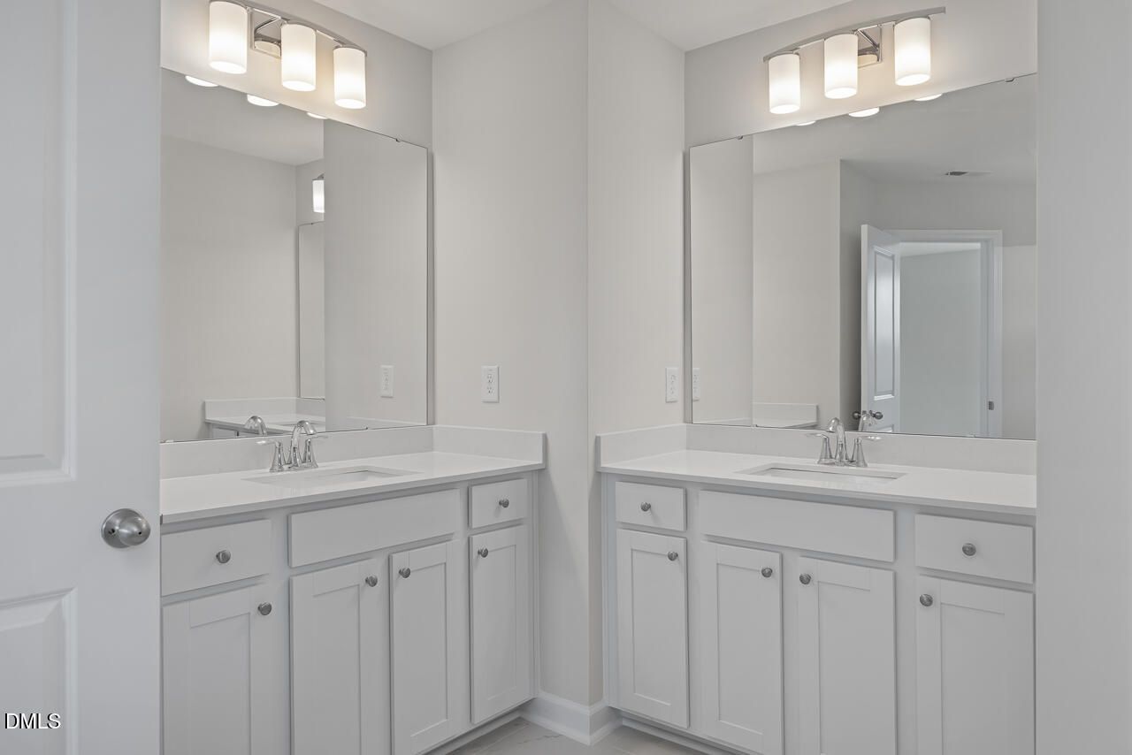 Modern double vanity with white shaker cabinets, quartz counters, and sconce lighting in Davidson Homes The Graham bathroom, Fuquay-Varina, NC