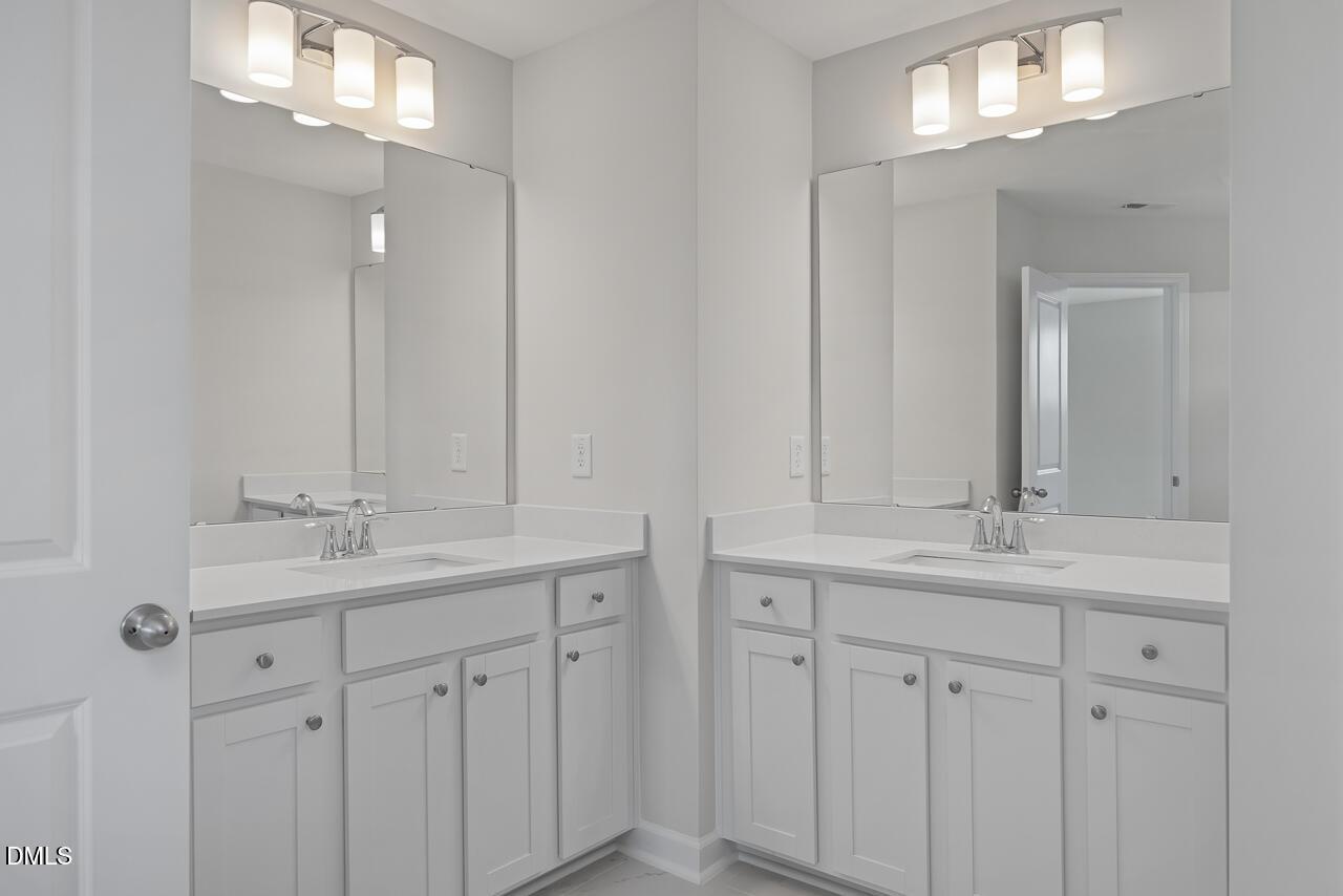 Modern double vanity with white shaker cabinets, quartz counters, and sconce lighting in Davidson Homes The Graham bathroom, Fuquay-Varina, NC