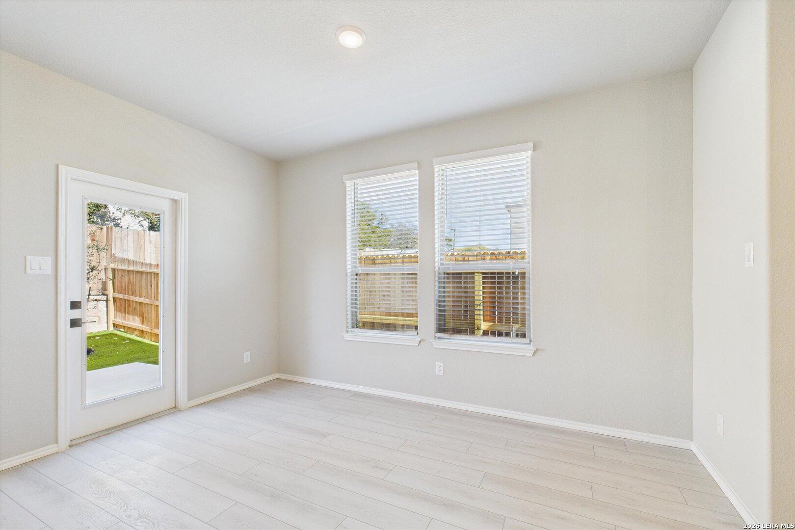Bright sunroom with large windows, blinds, and open door to fenced backyard in Davidson Homes The Charlotte A, San Antonio