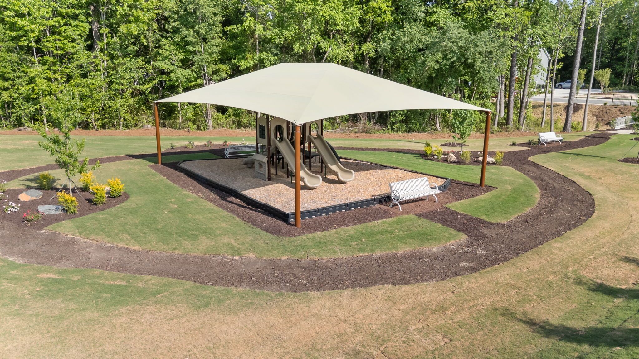 Community playground at Wendell Ridge in Wendell, NC with shaded play equipment, mulched ground, and park benches.