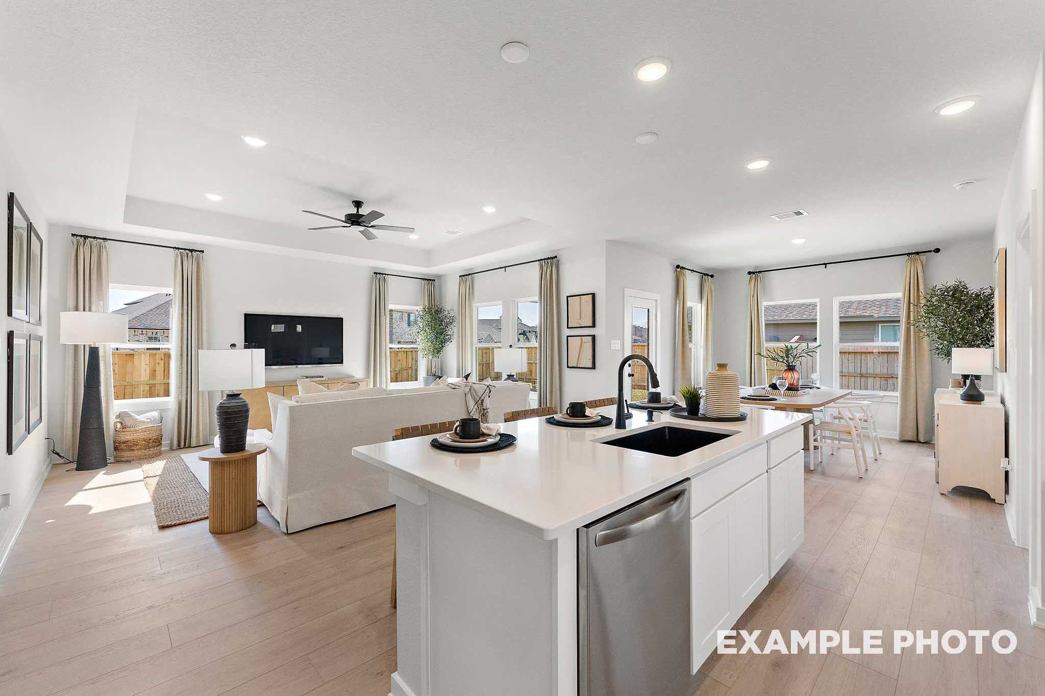 Spacious open-concept kitchen and living area in The Everett E with white island, hardwood floors, large windows, and modern decor