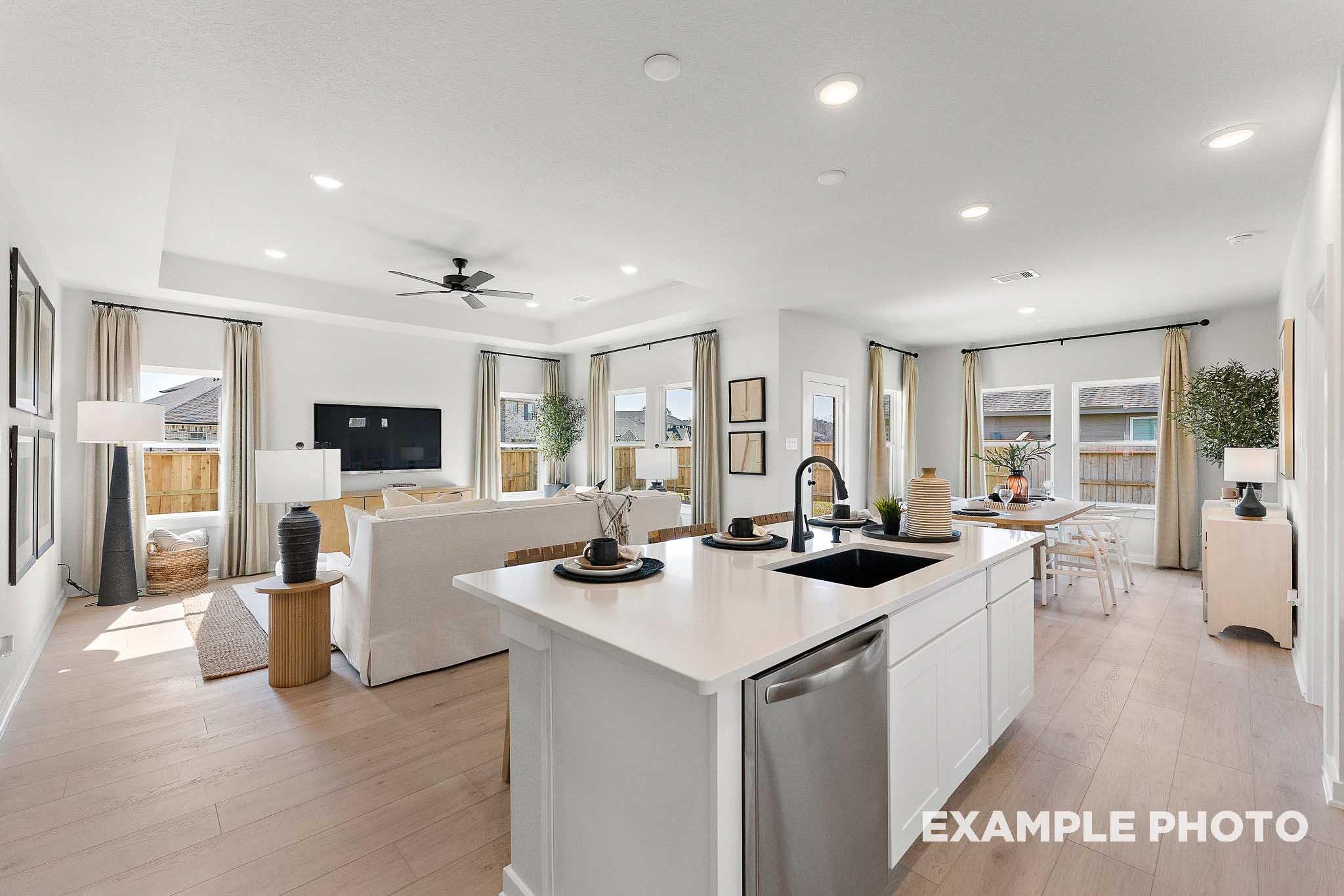 Spacious open-concept kitchen and living area in The Everett E with white island, hardwood floors, large windows, and modern decor