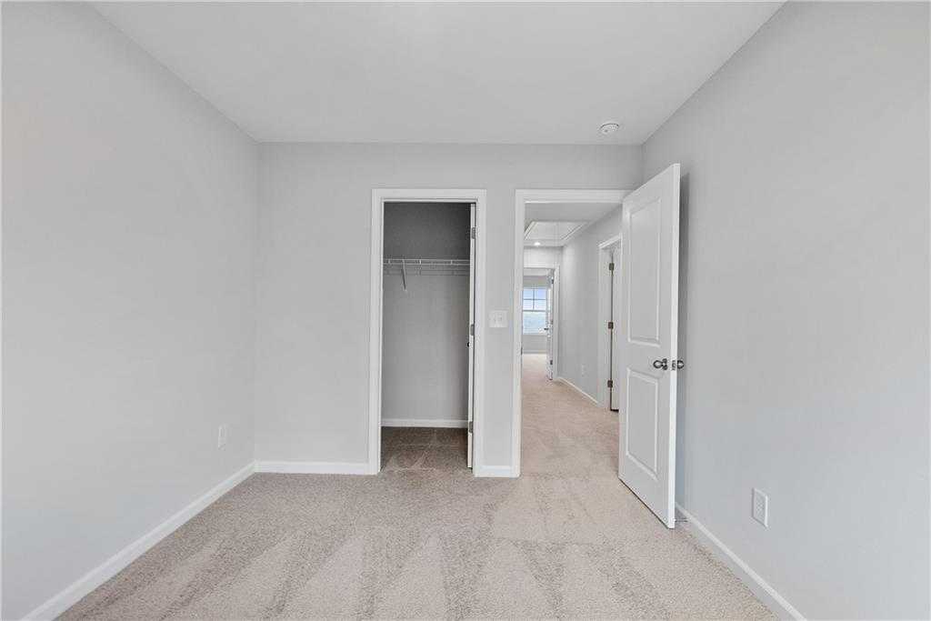 Spacious secondary bedroom with gray walls, carpet floors, and open closet in Davidson Homes The Durant A, Emerson, Georgia