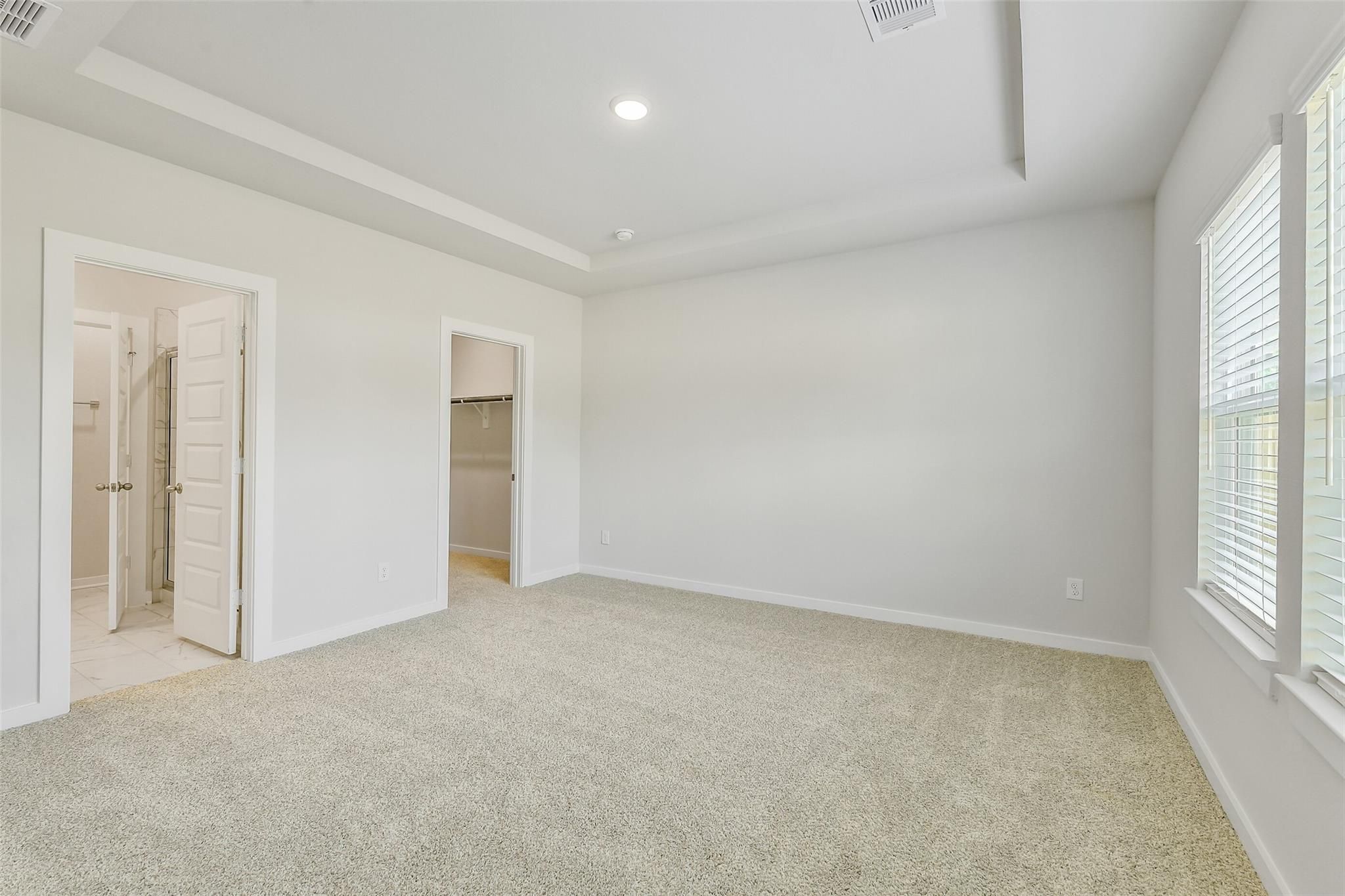 Spacious master bedroom with en-suite bathroom, walk-in closet, and large window in Davidson Homes San Marcos E, Conroe Texas
