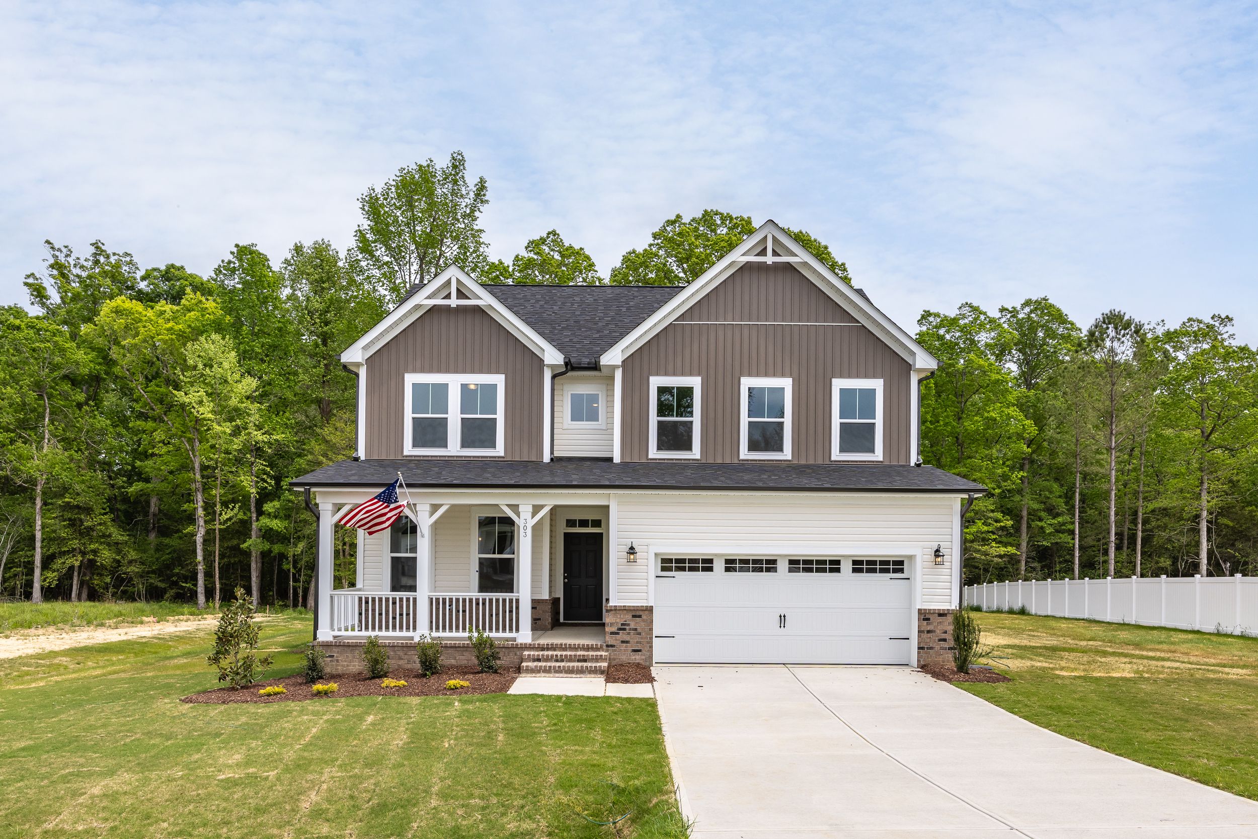 Modern craftsman-style two-story home at Montrose in Aberdeen, NC with covered front porch, American flag, and garage