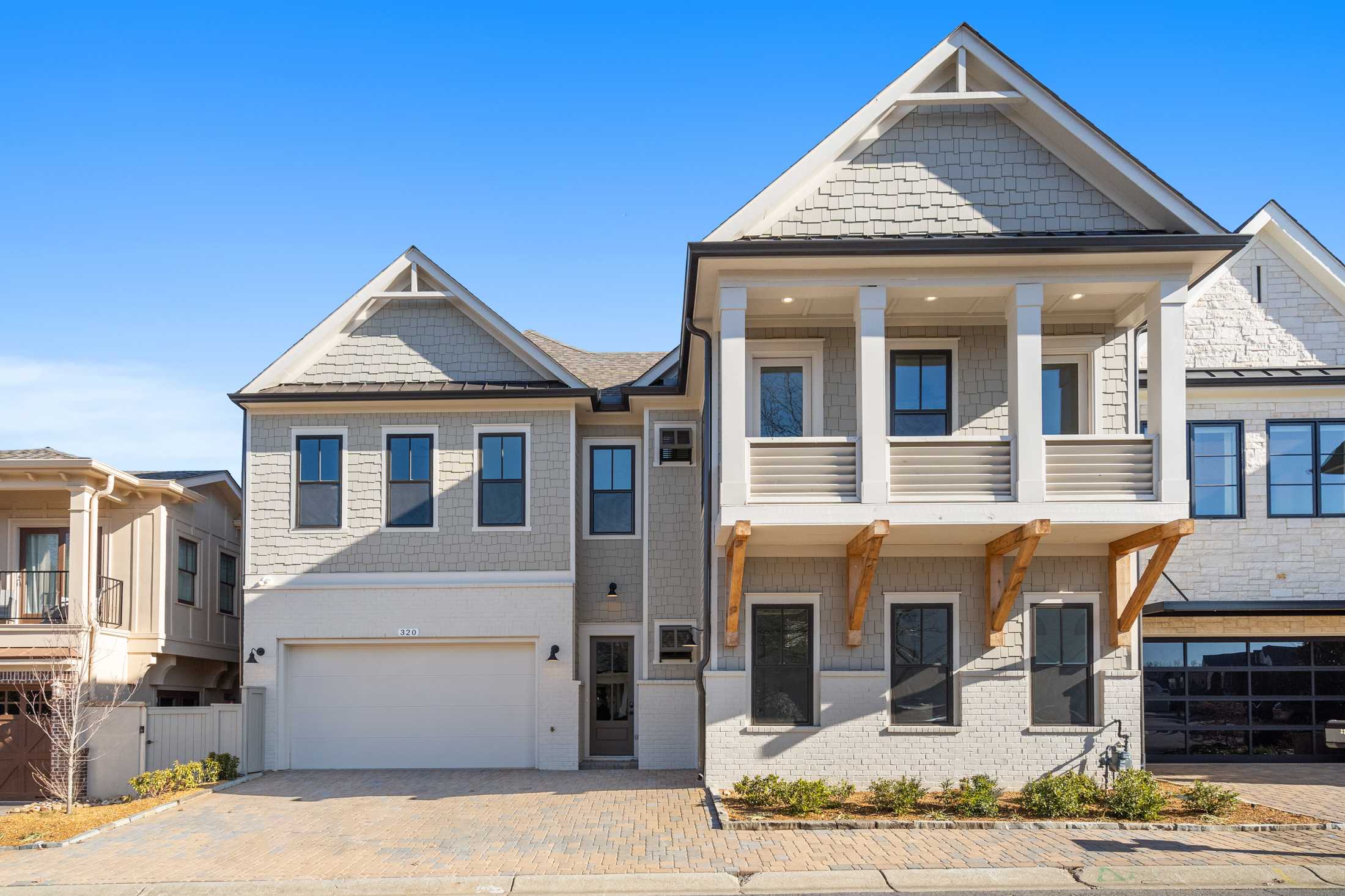 Modern two-story Seaside home elevation with shake siding, upper balcony, and three-car garage in Woodstock, GA