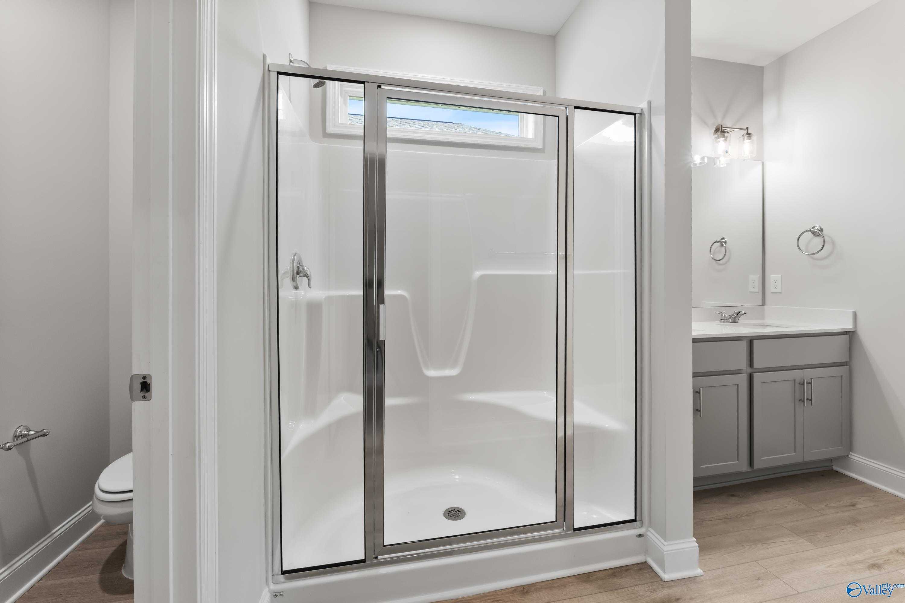 Modern master bathroom with frameless glass shower, single vanity, and neutral tones in Davidson Homes The Daphne C, Huntsville, Alabama