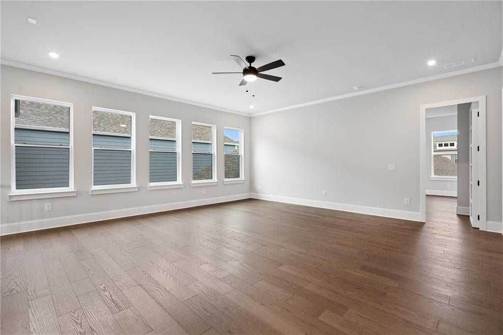 Spacious great room with hardwood floors, large windows, ceiling fan in Davidson Homes The Seaside B, Woodstock, Georgia