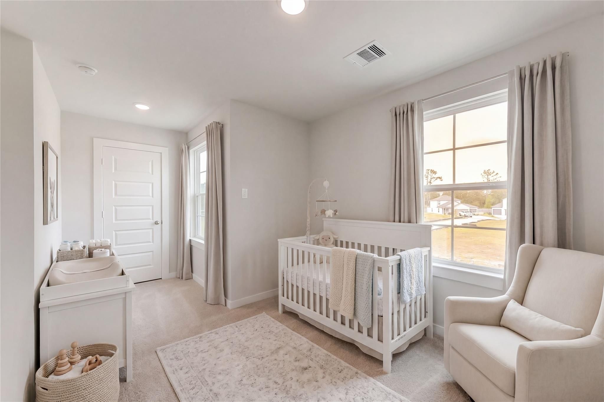 Cozy nursery featuring white crib with blankets, changing table, and glider chair in Davidson Homes The Brazos E, Dayton, Texas