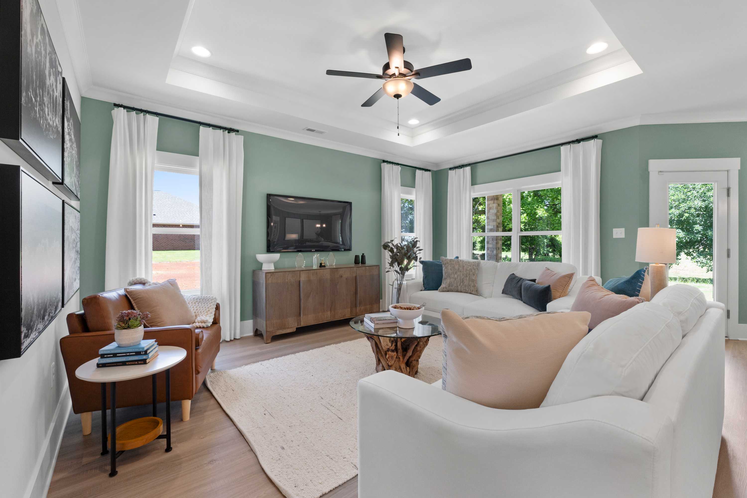Spacious living room at Hollon Meadow in Decatur Alabama with white sofas, hardwood floors, ceiling fan and large windows