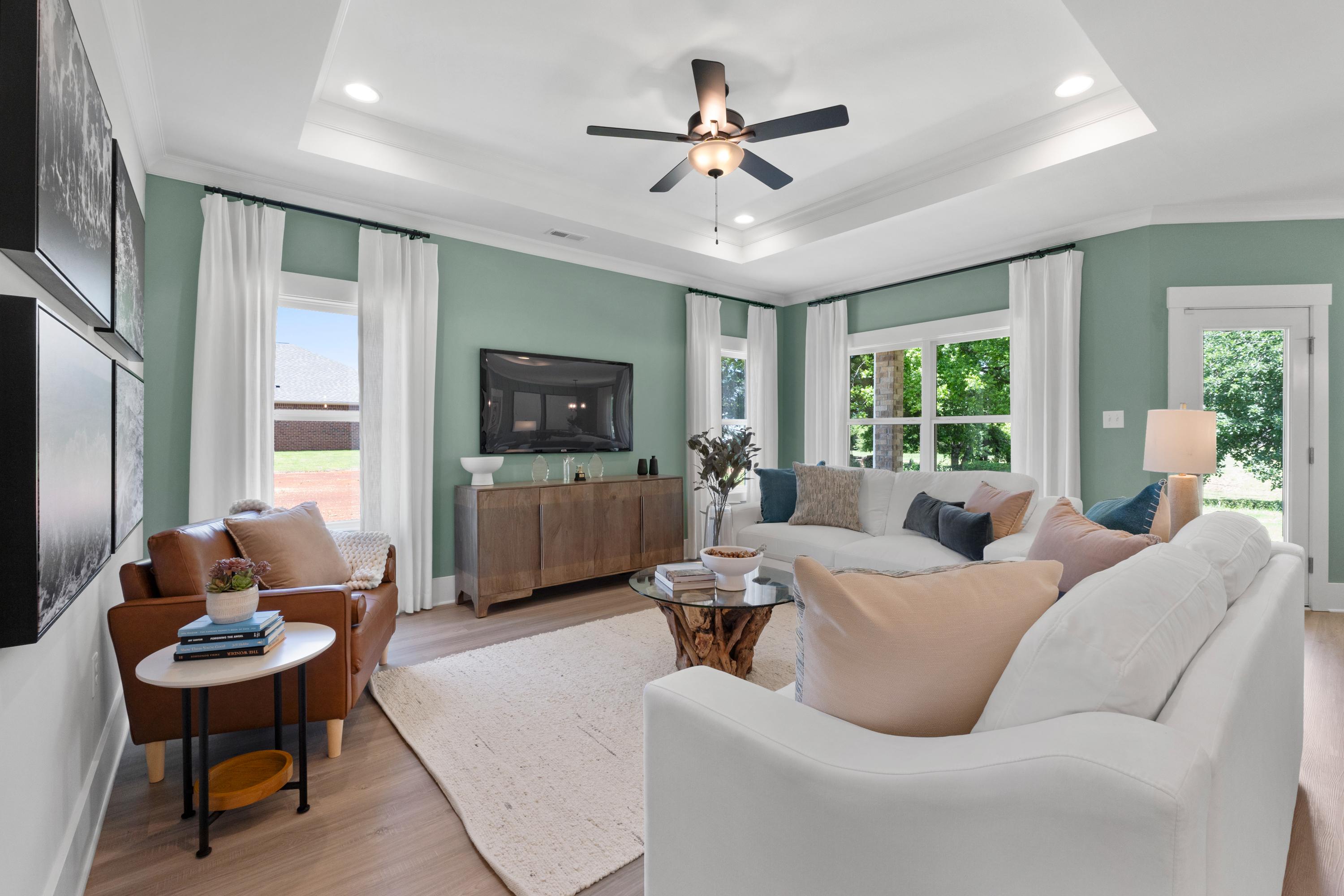 Spacious living room at Hollon Meadow in Decatur Alabama with white sofas, hardwood floors, ceiling fan and large windows