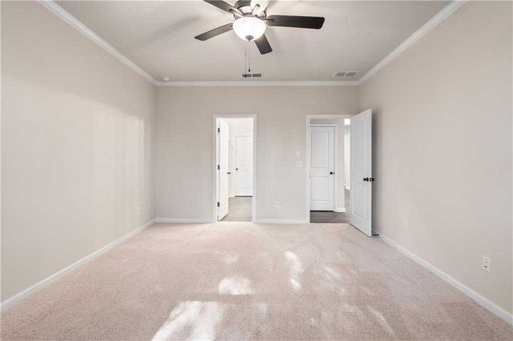 Bright secondary bedroom with ceiling fan, beige carpet, and open closet doors in Davidson Homes The Daphne B, Loganville, GA