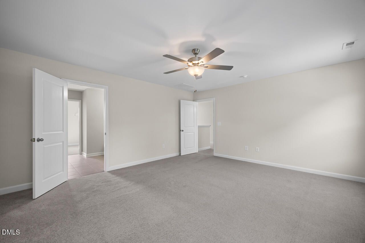 Spacious carpeted bedroom with ceiling fan and white doors in Davidson Homes The Willow C plan, Woodland Crossing, Zebulon NC
