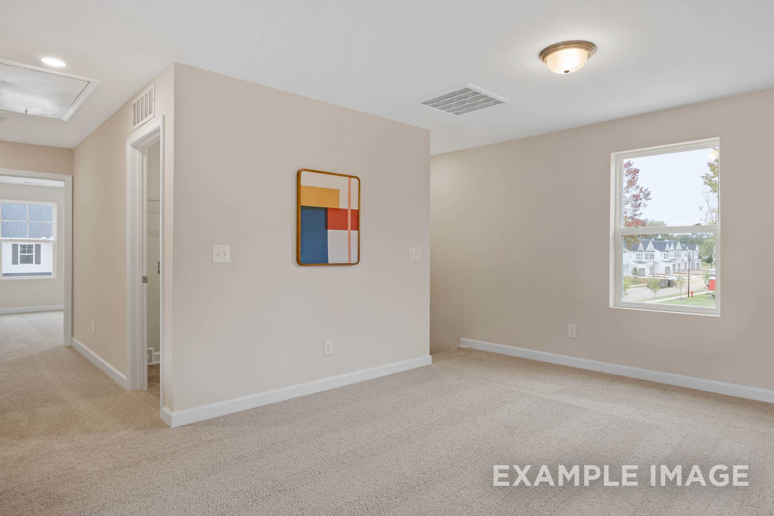 Spacious empty bedroom in The Preston B with beige walls, carpet floor, abstract geometric art, and large window overlooking neighborhood