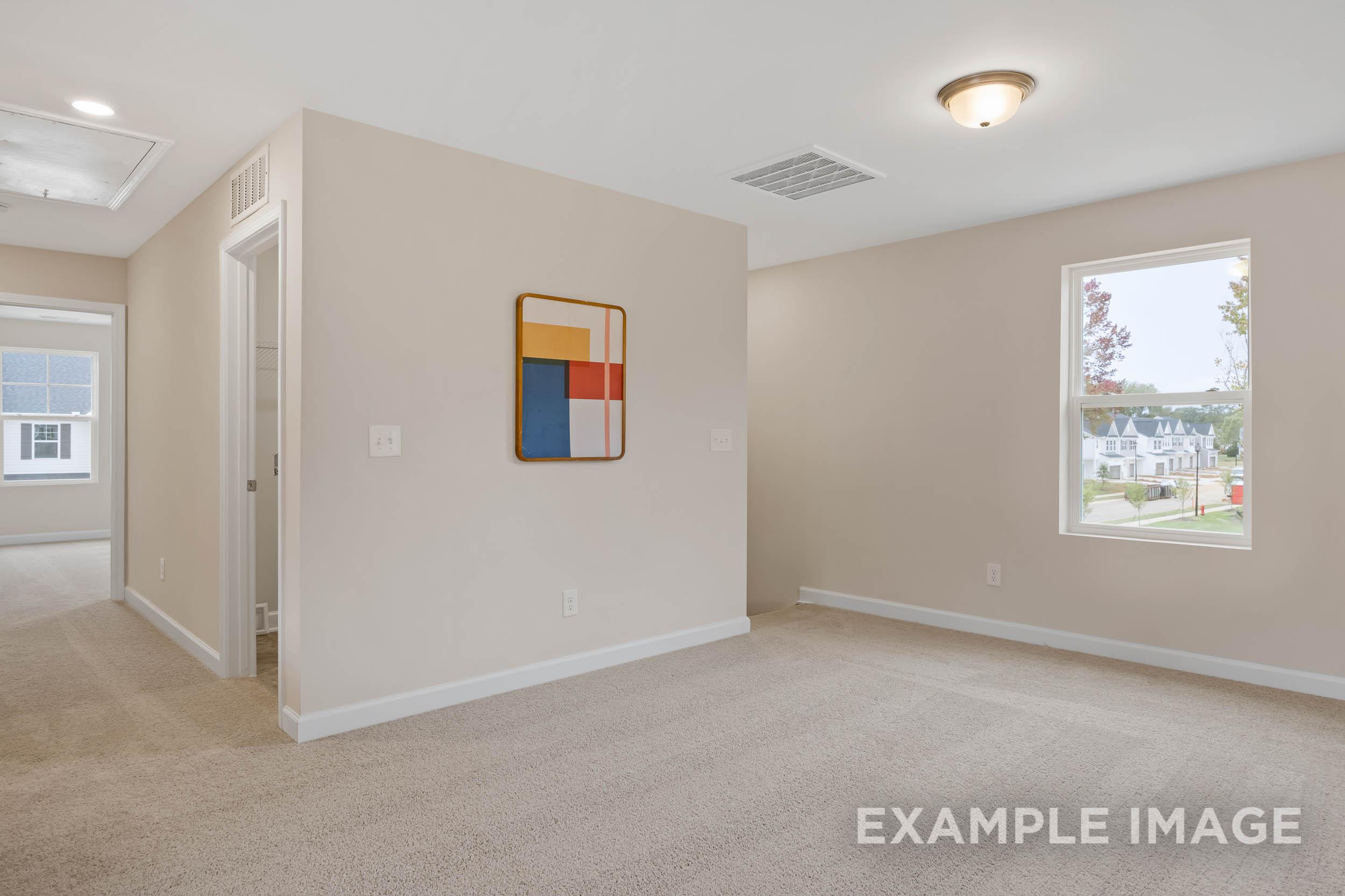 Spacious empty bedroom in The Preston B with beige walls, carpet floor, abstract geometric art, and large window overlooking neighborhood