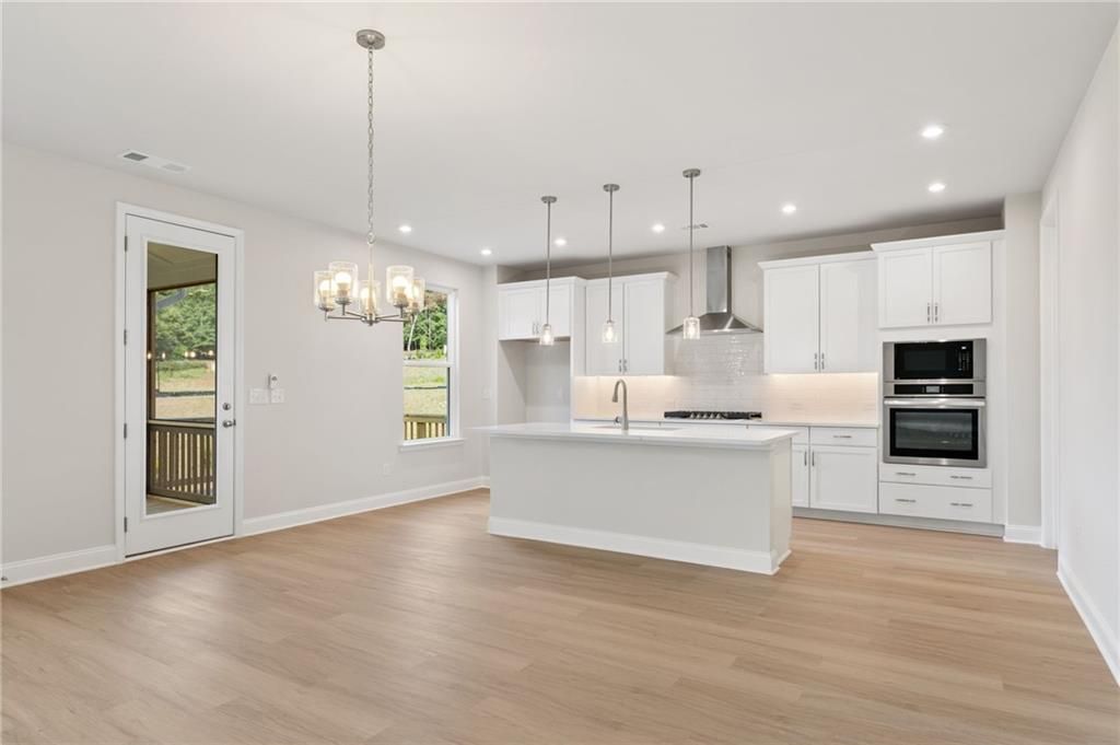 Modern open-concept kitchen with white island, stainless appliances, and pendant lights in Davidson Homes The Hampton C, Buford, GA