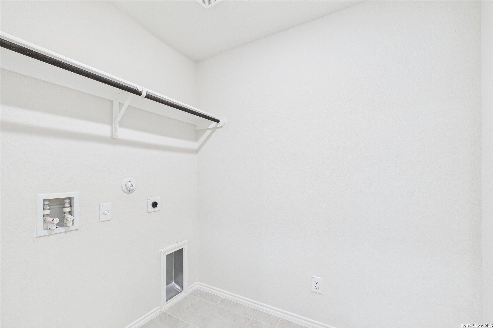 Bright white laundry room with utility sink, washer hookups, and hanging rod in The Gillian B by Davidson Homes, San Antonio
