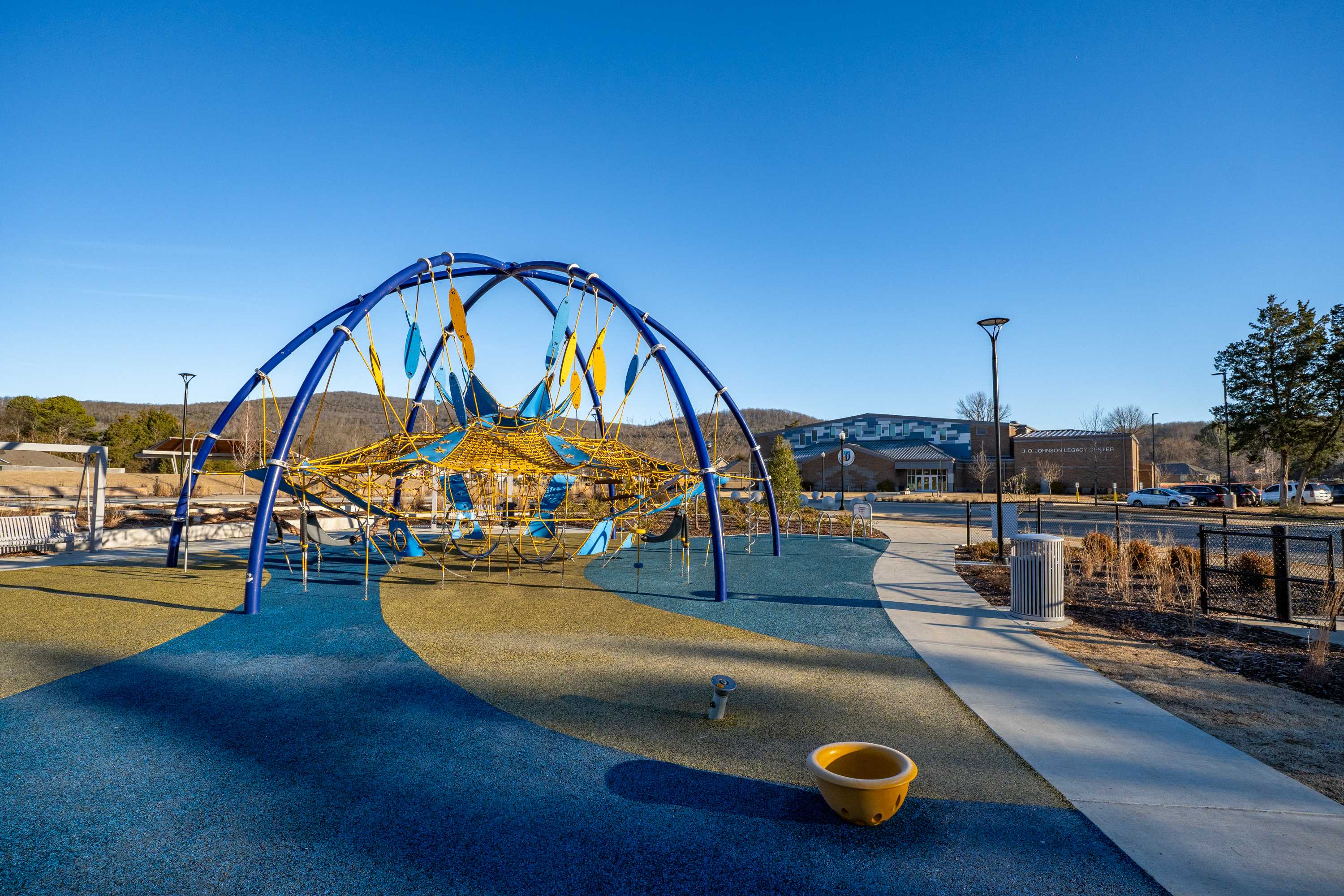 Vibrant playground at Jaguar Hills in Huntsville Alabama featuring blue dome climbing nets and yellow bucket seats