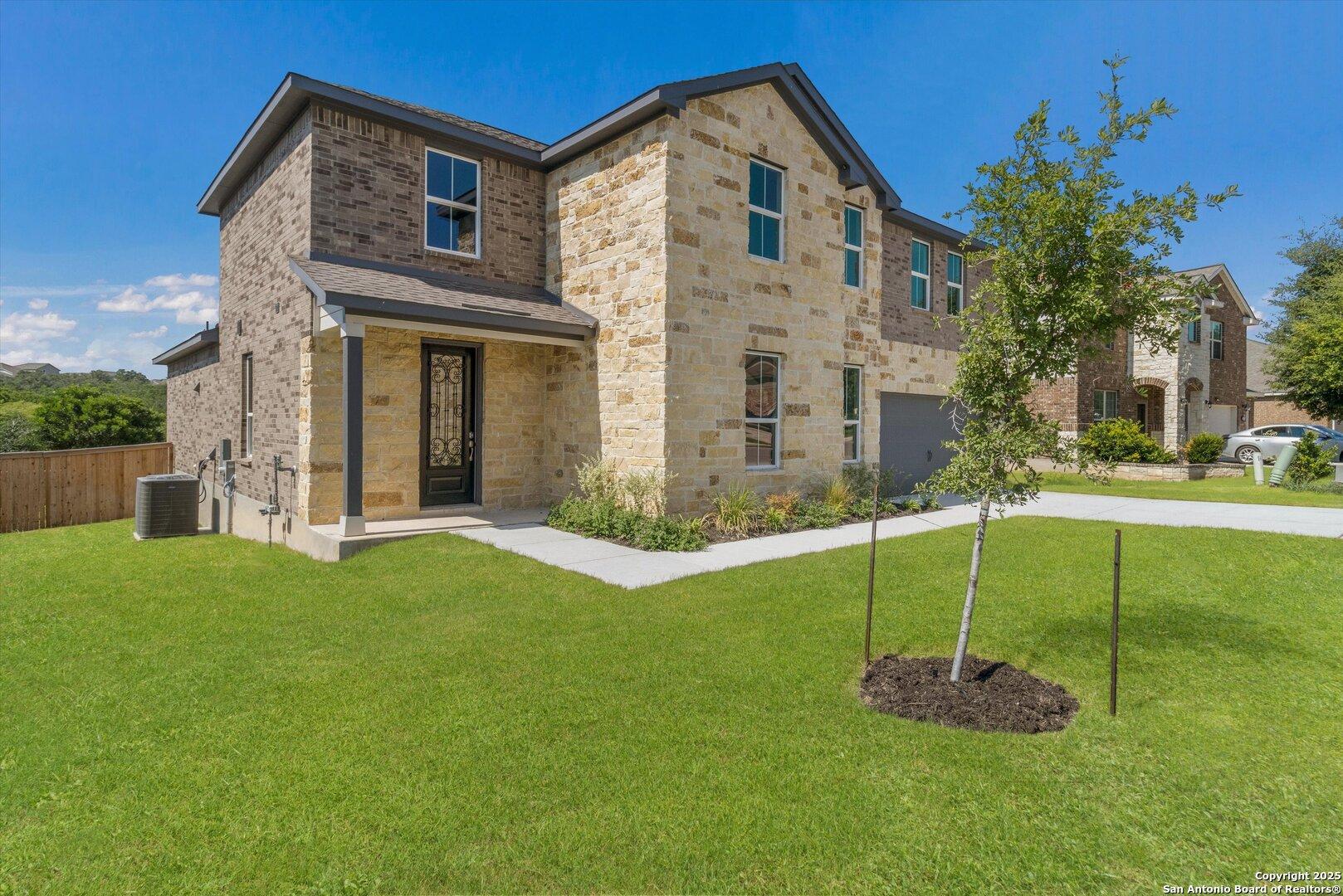 Two-story brick and stone home with 2-car garage, covered porch, and landscaped yard in Ladera, San Antonio, Texas - Davidson Homes Jennings H