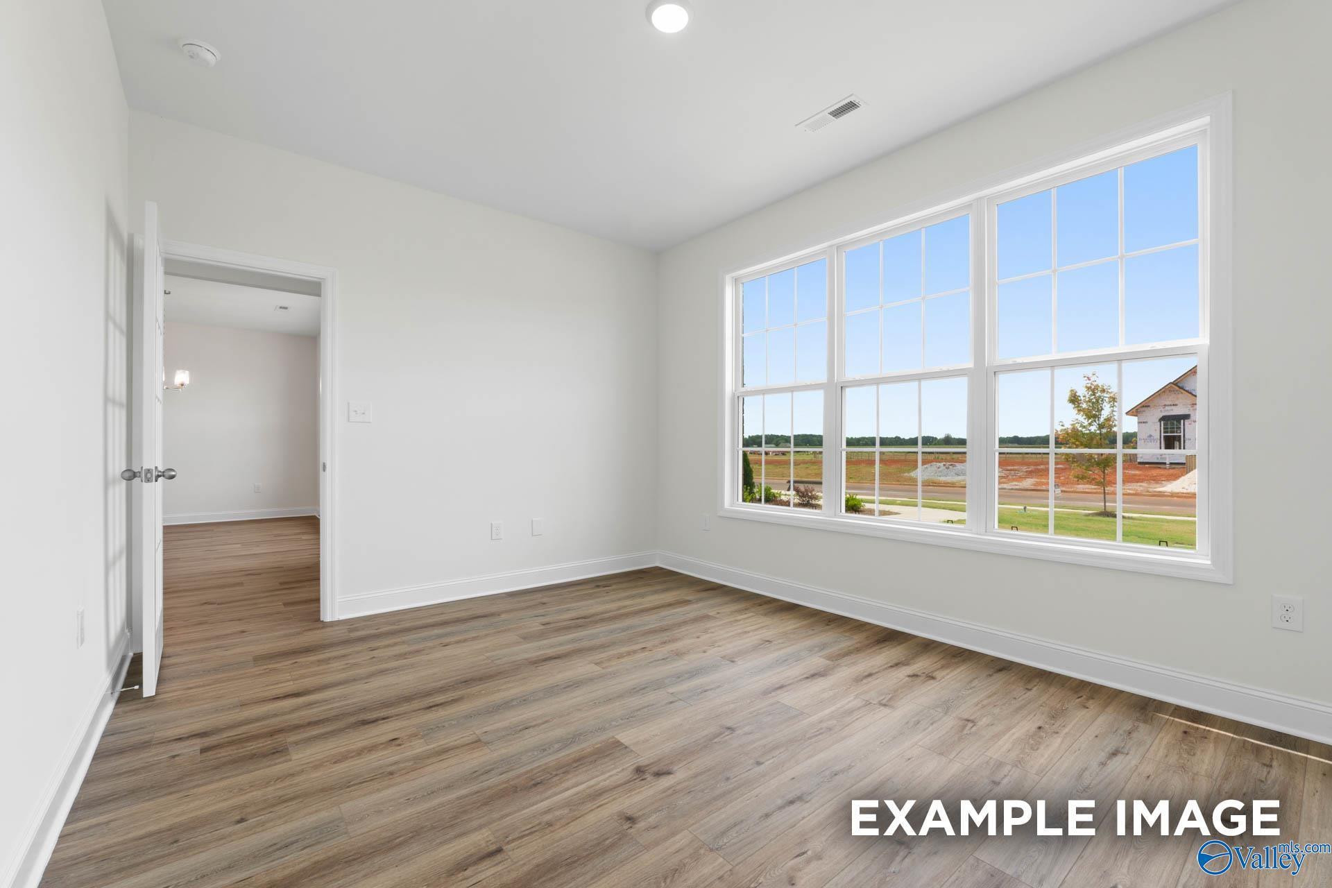 Bright secondary bedroom with hardwood floors and large windows overlooking green space in Davidson Homes The Oxford, Riverton Preserve, Huntsville