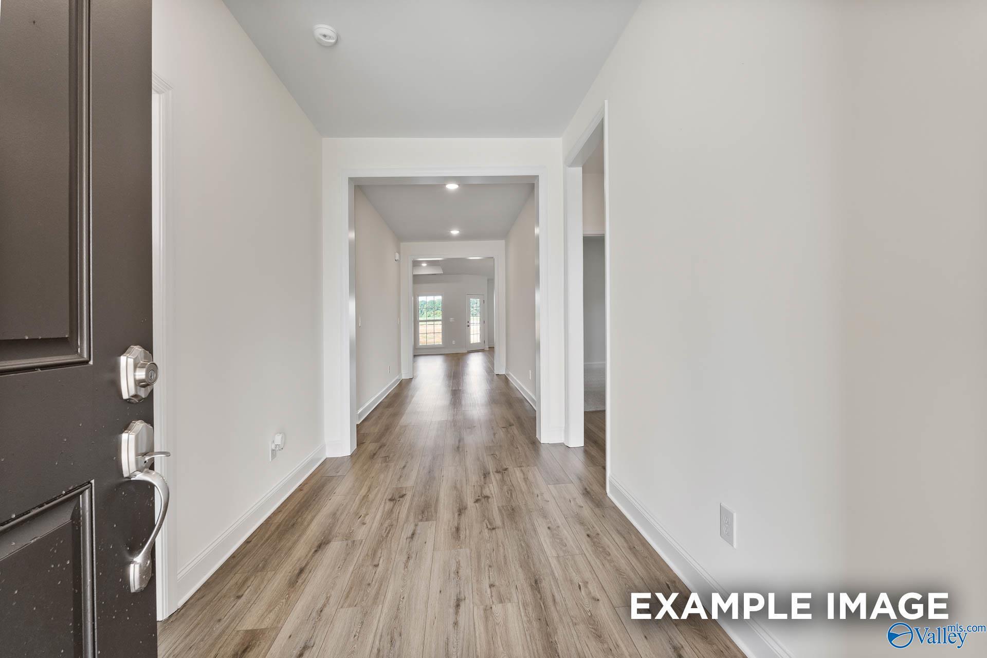 Bright entry foyer with black front door, hardwood floors, and open archways in Davidson Homes The Harrison C, Athens Alabama