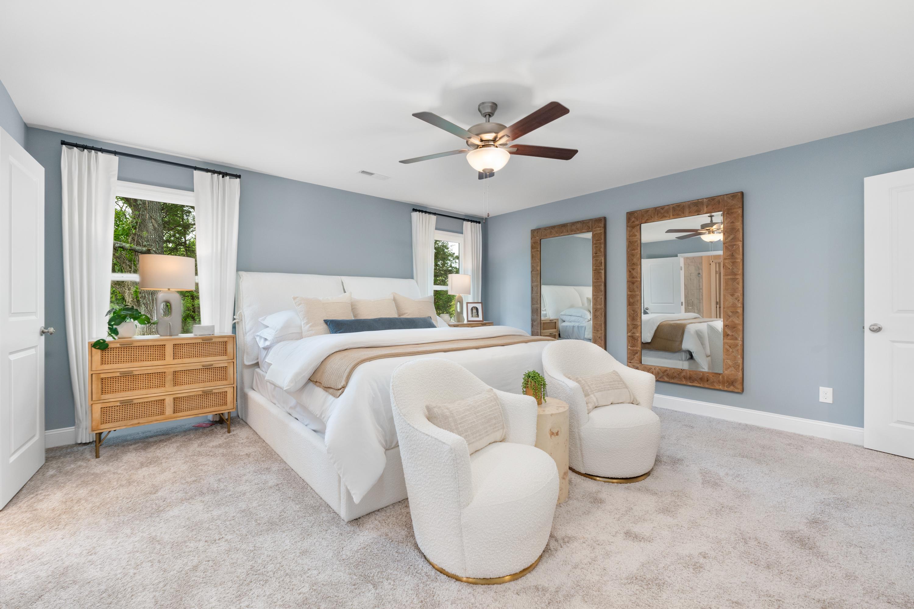 Spacious primary bedroom in Pavilion Huntsville Alabama with light blue walls, king bed, wooden mirrors, and accent chairs