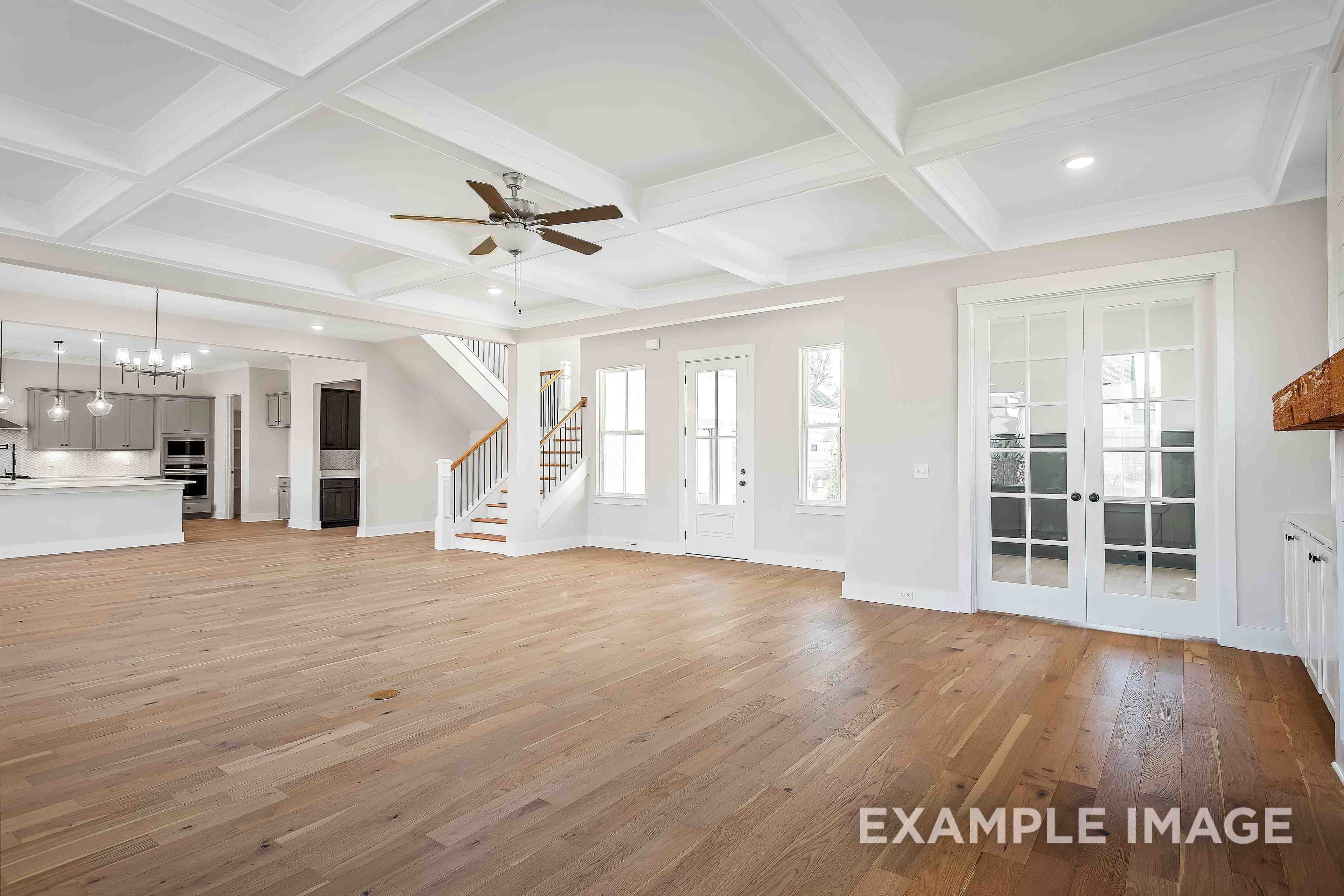 Spacious open-concept living area in The Alston A with hardwood floors, coffered ceiling, ceiling fan, staircase, and kitchen island