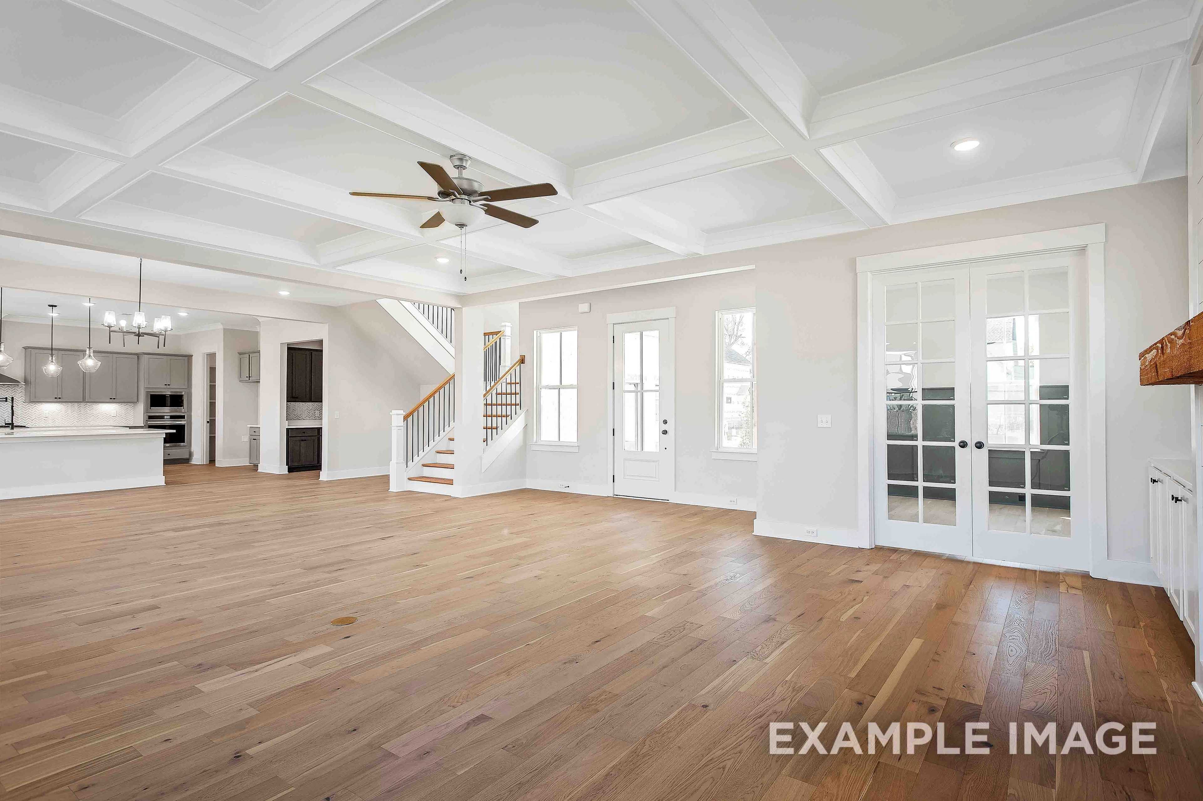 Spacious open-concept living area in The Alston A with hardwood floors, coffered ceiling, ceiling fan, staircase, and kitchen island