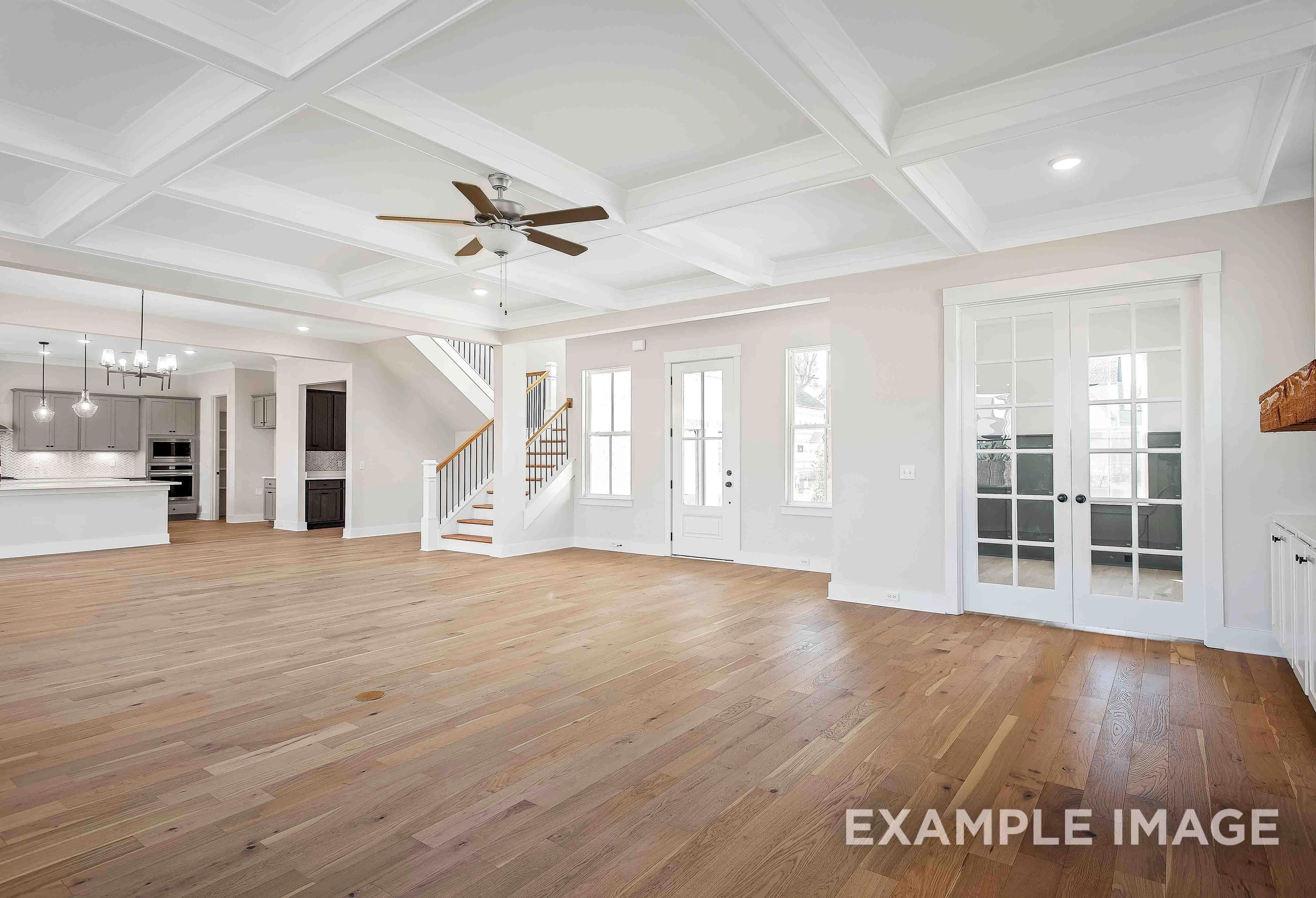 Spacious open-concept living area in The Alston A with hardwood floors, coffered ceiling, ceiling fan, staircase, and kitchen island