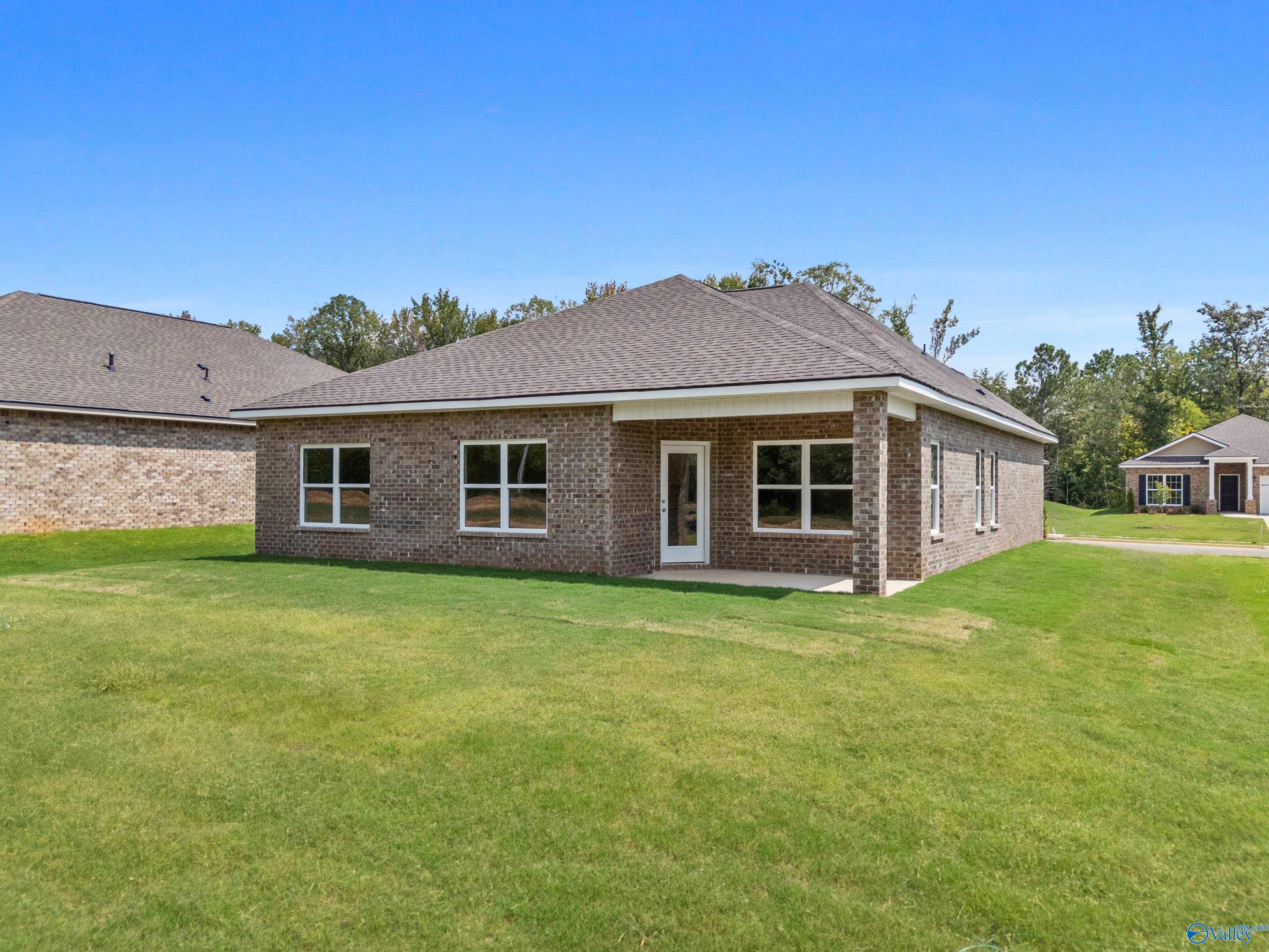 Brick single-story home with gabled roof, large windows, and covered entry on green lawn in Spragins Cove, Huntsville, Alabama