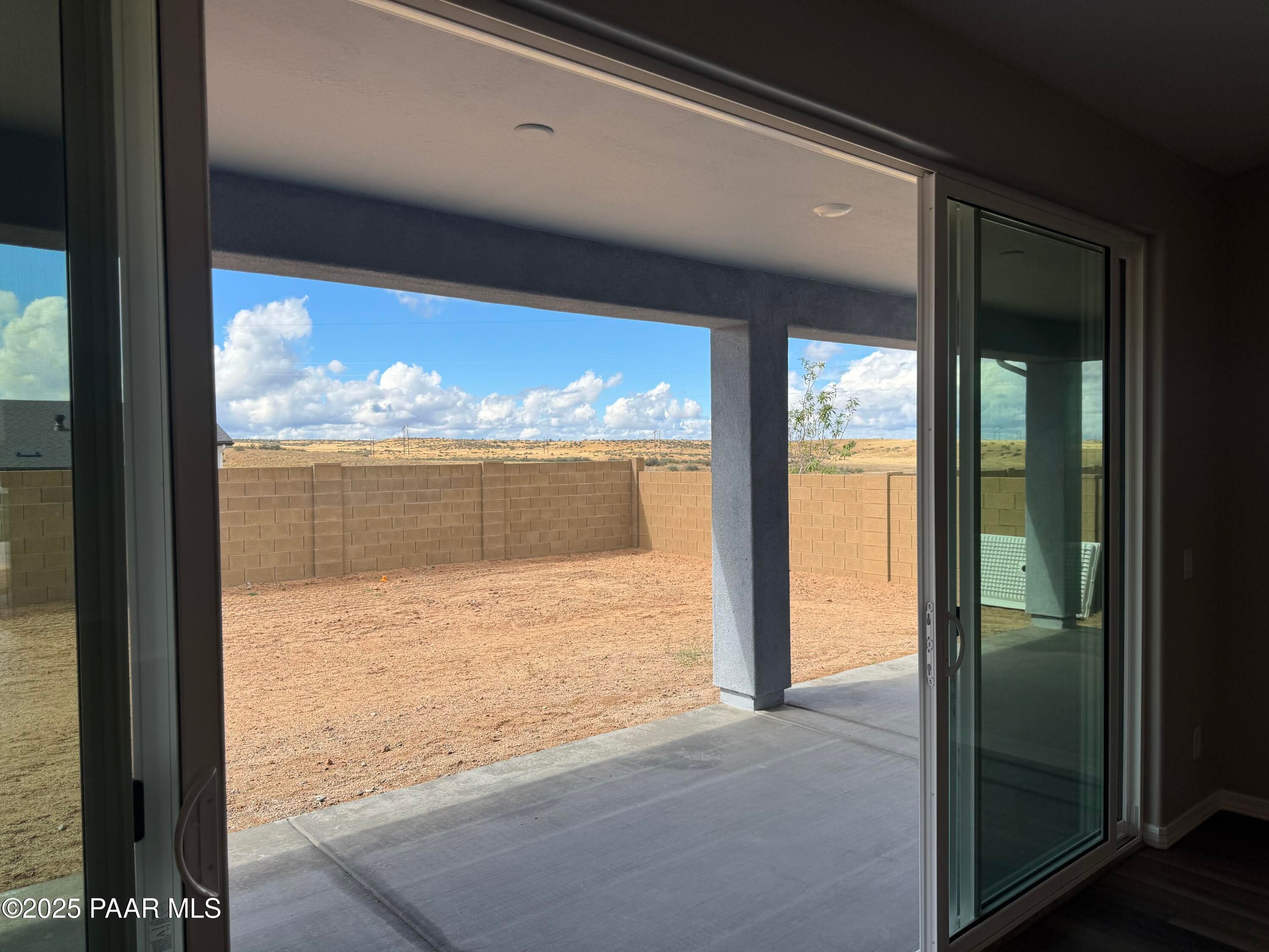 Open sliding glass doors to covered patio with desert backyard view and distant mountains in Davidson Homes The Monarch A, Prescott, Arizona