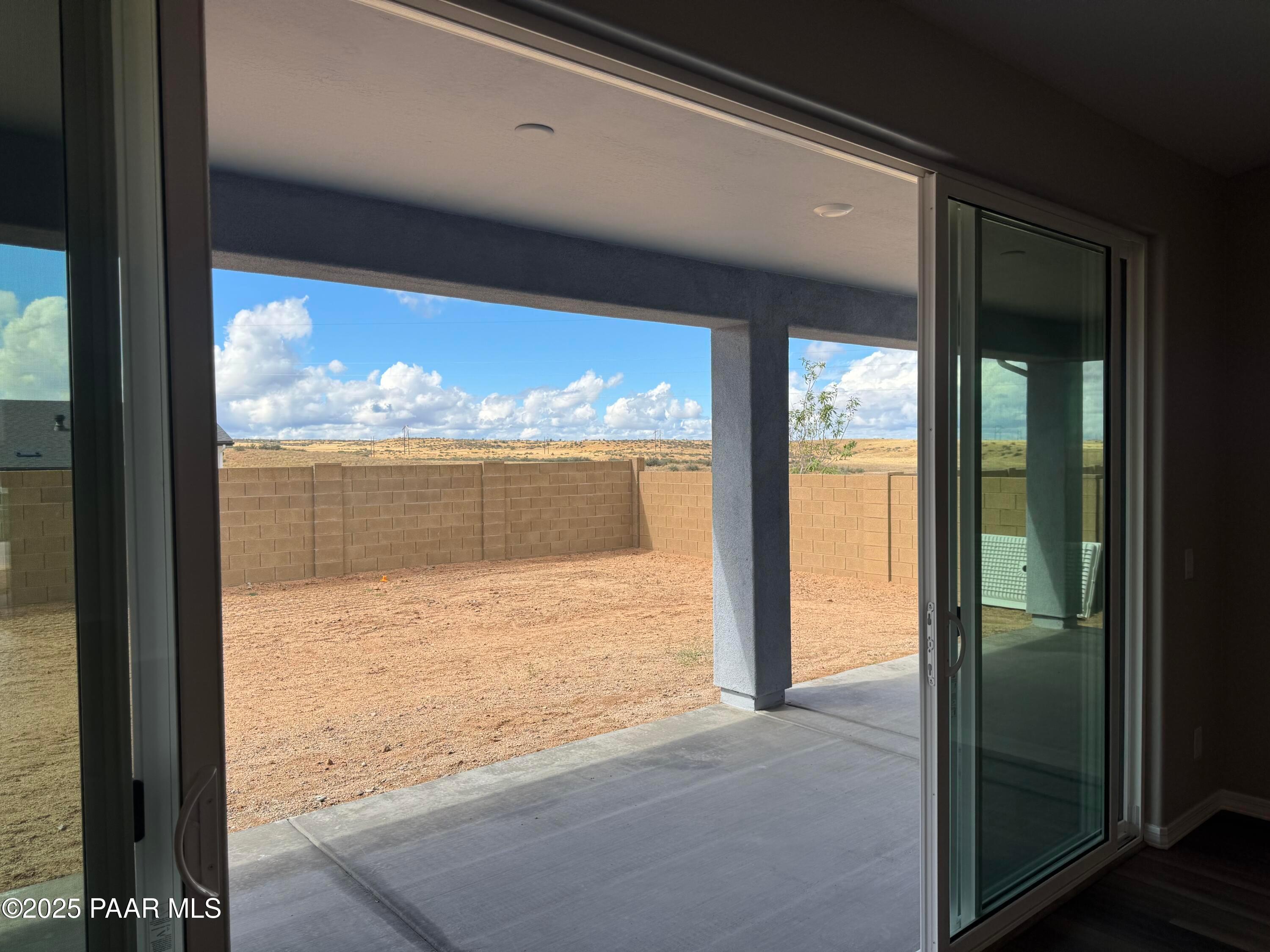 Open sliding glass doors to covered patio with desert backyard view and distant mountains in Davidson Homes The Monarch A, Prescott, Arizona