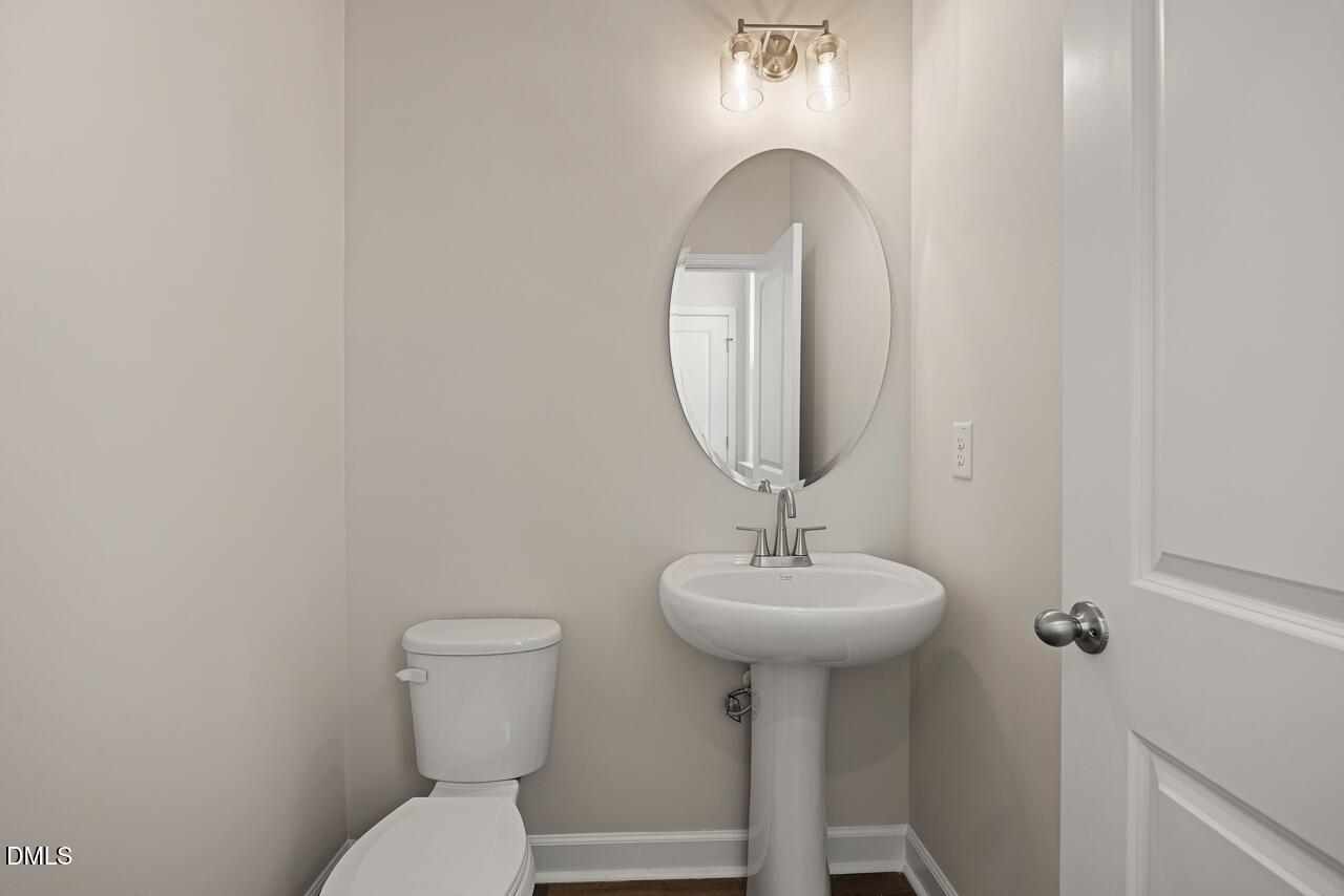Half bathroom with pedestal sink and oval mirror in The Alexander C floor plan at Forestville Yard, Knightdale, NC.