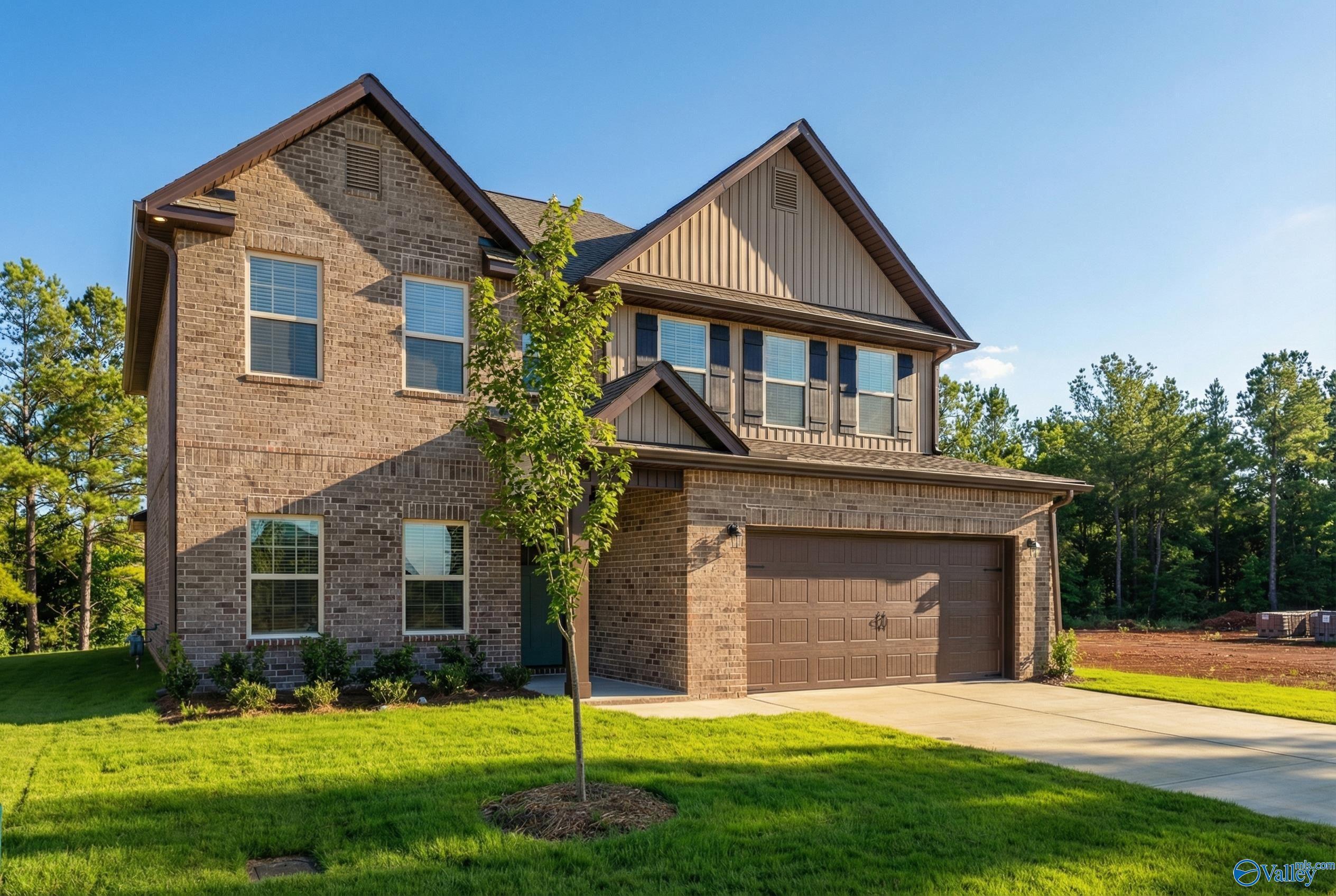 Two-story brick Shelby A home with 2-car garage, lush lawn, and trees in Ricketts Farm, Athens, Alabama