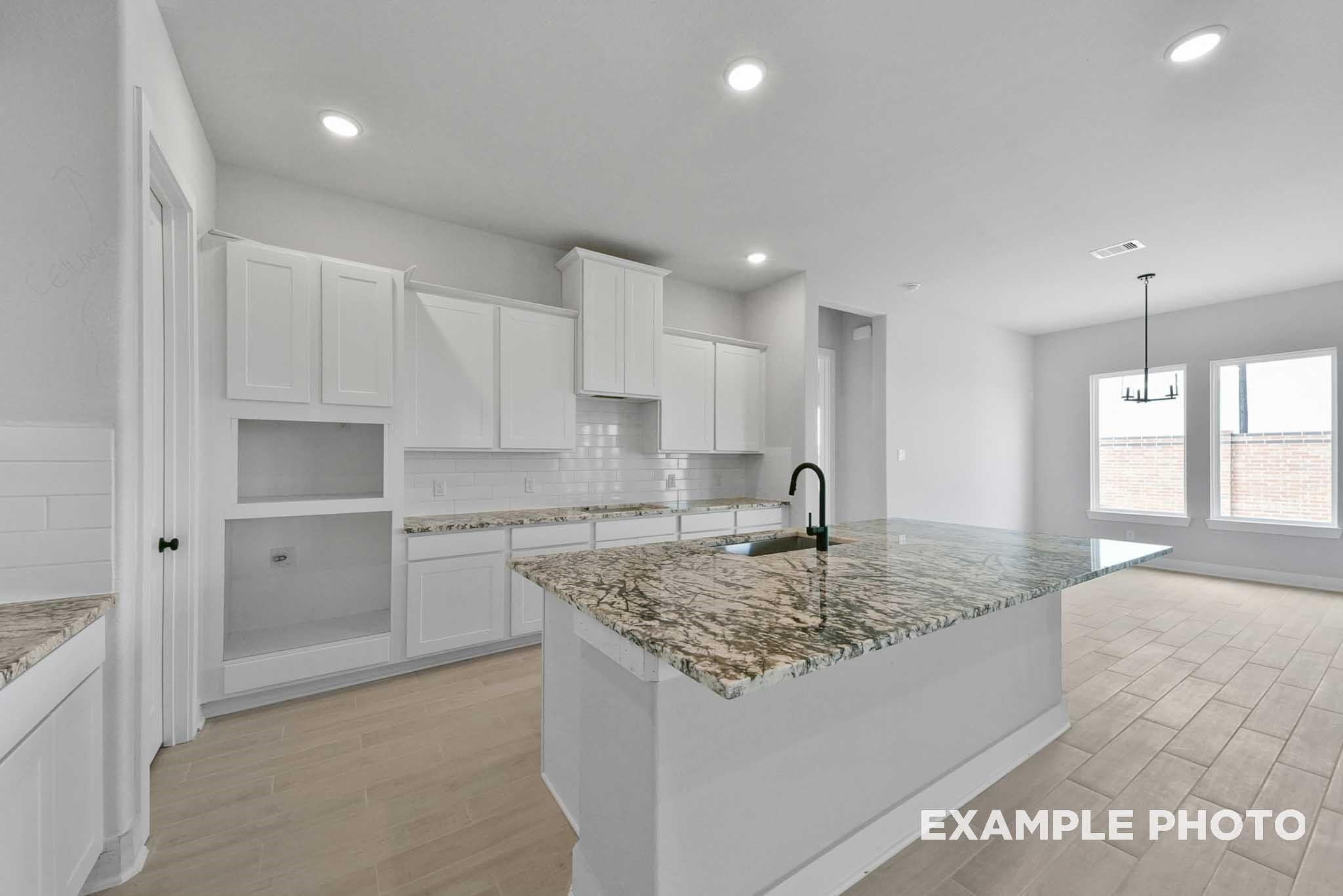 Modern kitchen with white shaker cabinets, granite island, stainless faucet in Davidson Homes The George A, Lago Mar, Texas City