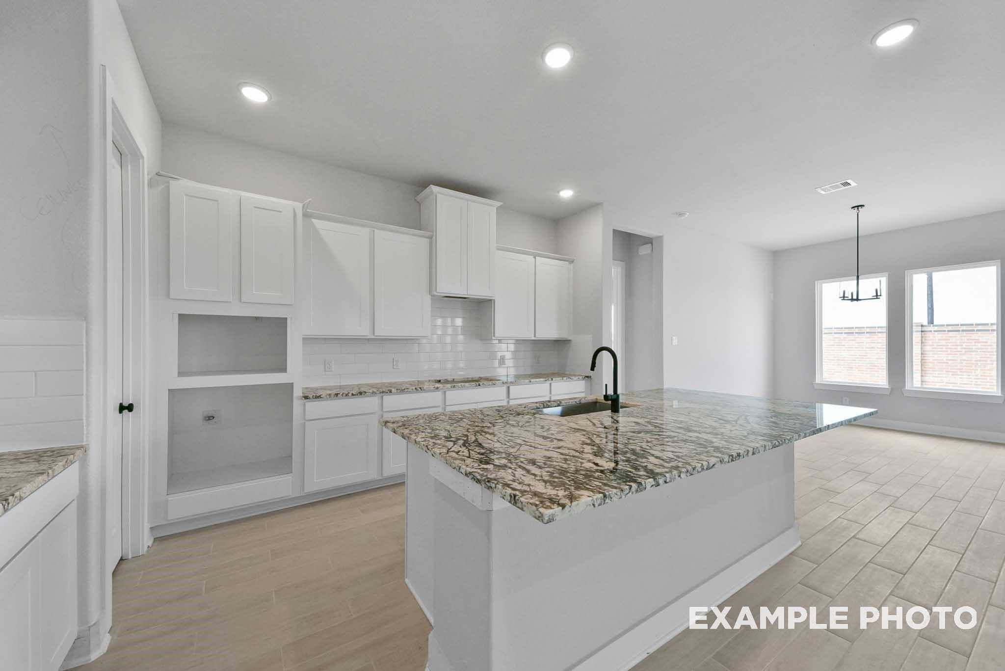 Modern kitchen with white shaker cabinets, granite island, stainless faucet in Davidson Homes The George A, Lago Mar, Texas City