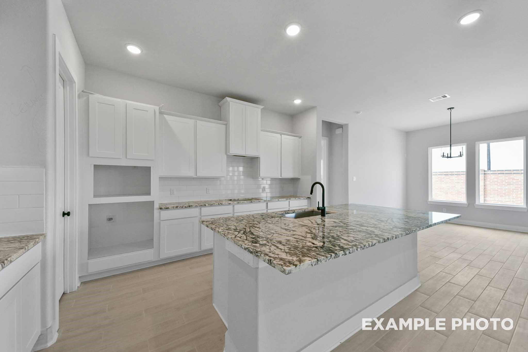Modern kitchen with white shaker cabinets, granite island, stainless faucet in Davidson Homes The George A, Lago Mar, Texas City