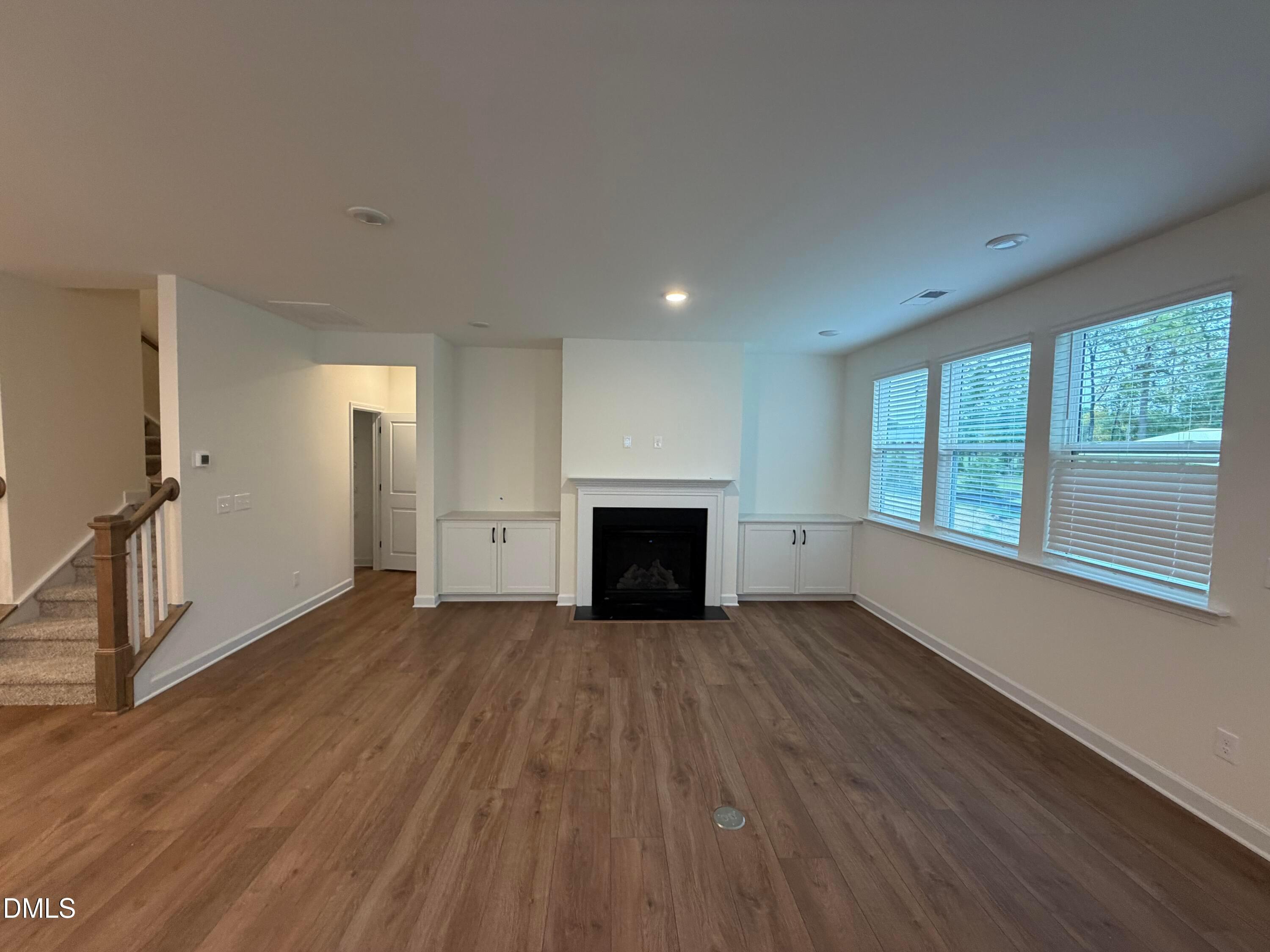 Bright family room with fireplace, built-in cabinets, hardwood floors, and staircase in Davidson Homes The Ashport M, Wendell Ridge, NC