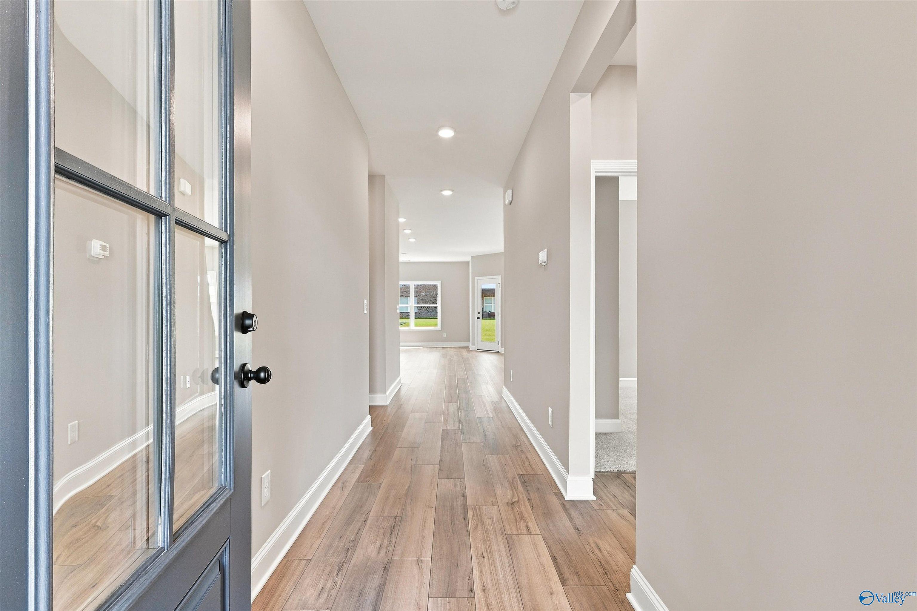 Bright entry foyer with glass-paneled front door and luxury vinyl plank flooring in Davidson Homes The Franklin C, Wood Trail, Toney, AL