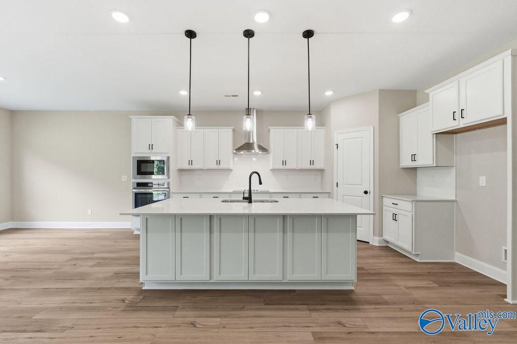 Modern kitchen with large island, white cabinets, and stainless appliances in The Rockford floor plan, Cain Park, Hartselle.