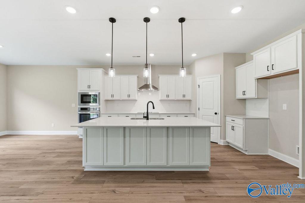 Modern kitchen with large island, white cabinets, and stainless appliances in The Rockford floor plan, Cain Park, Hartselle.