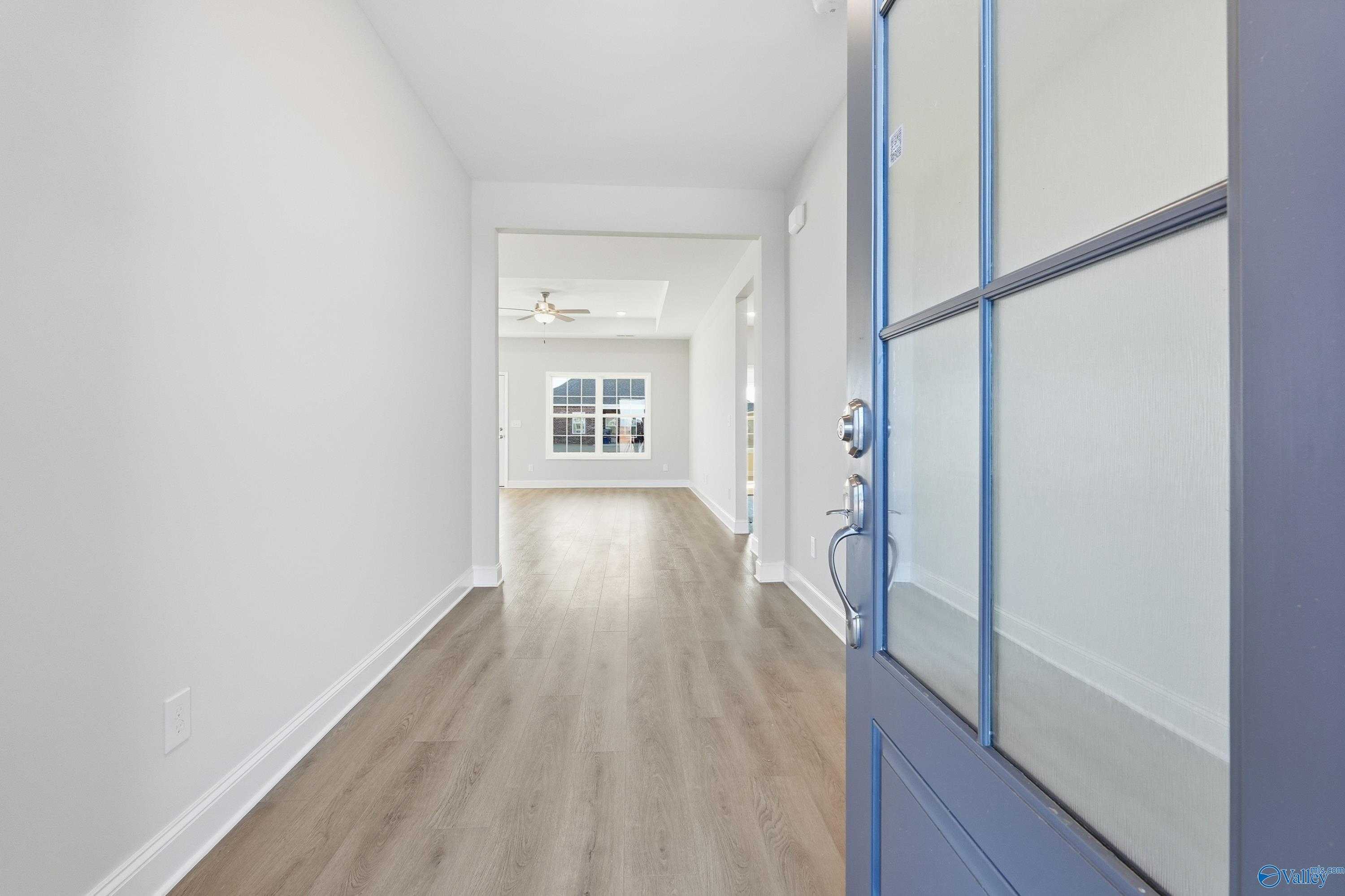 Welcoming entry hallway with light oak floors and blue glass front door in Davidson Homes The Montgomery B, Toney, Alabama
