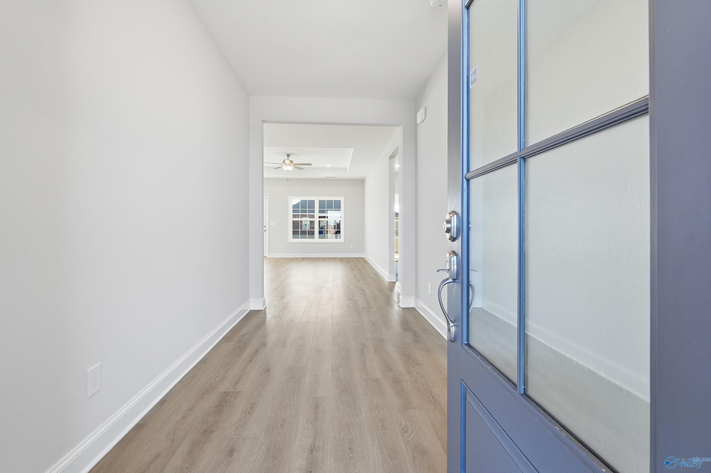 Bright entry hallway with light wood floors, white walls, and open glass-paneled front door in Davidson Homes Montgomery B, Toney AL